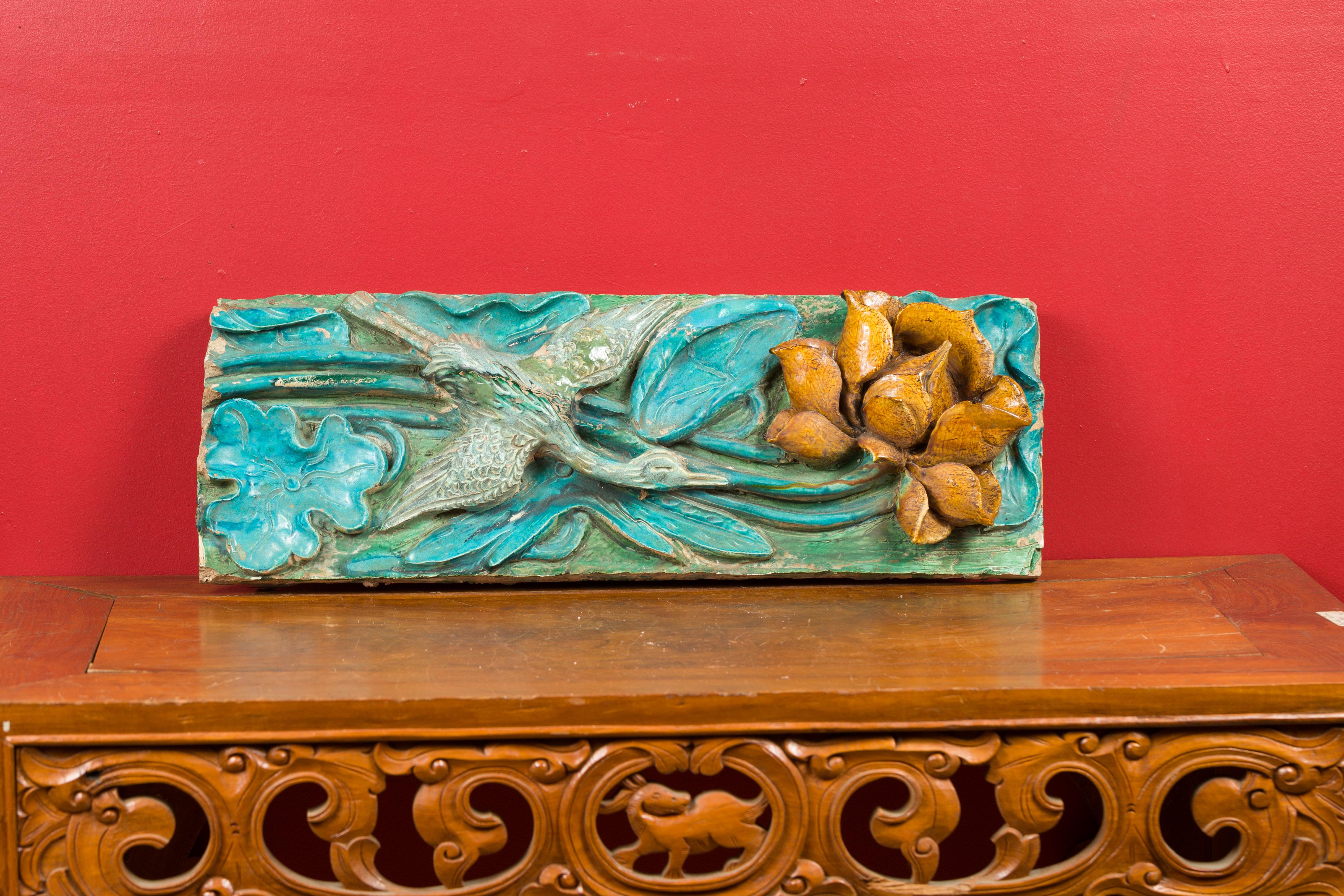 A Chinese Ming Dynasty period ancient roof tile with turquoise finish, crane and flower. Created in China during the Ming Dynasty (1368-1644), this ancient roof tile features a turquoise and green ground adorned with foliage. A crane is flying down