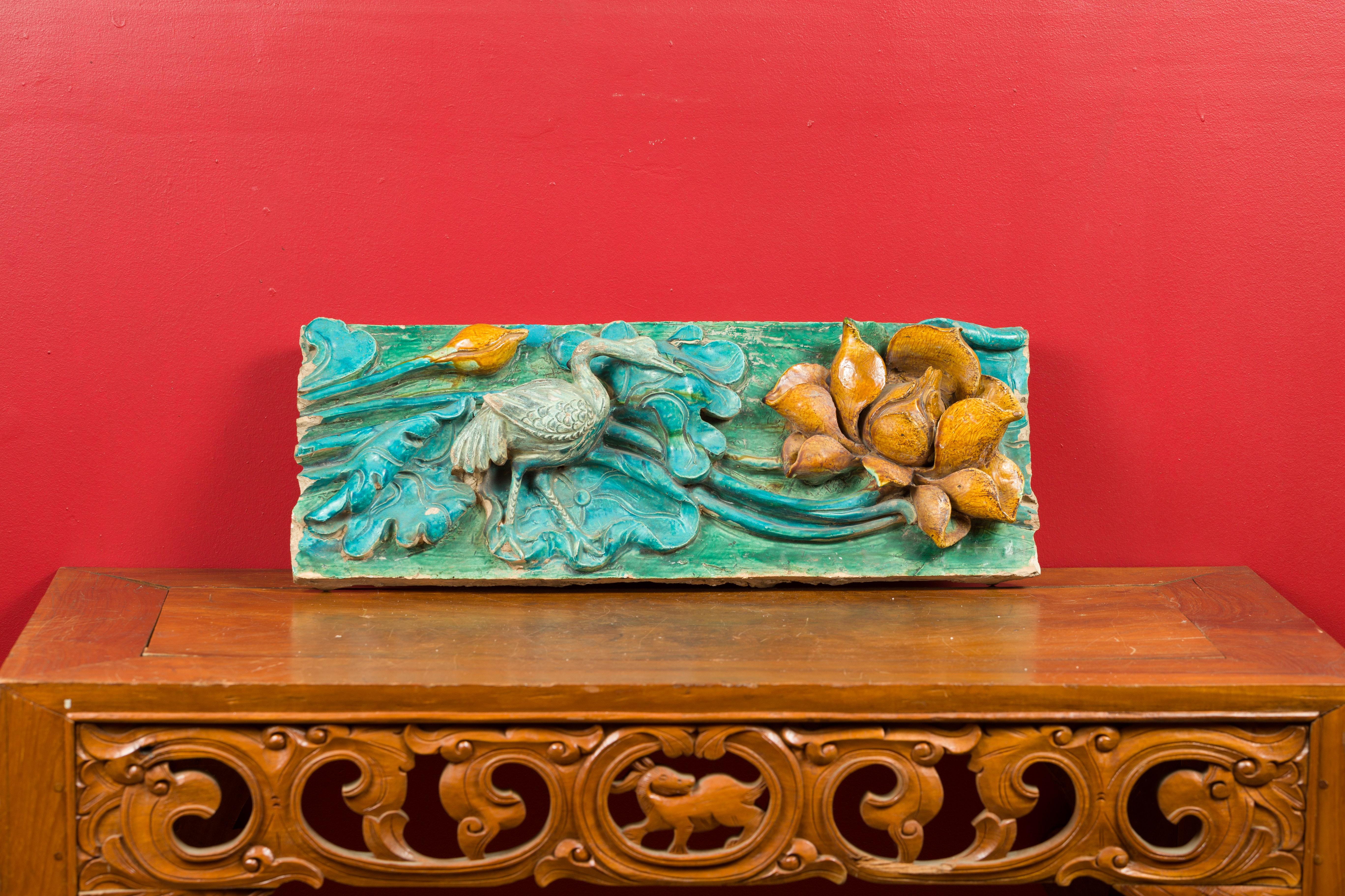 Tuile ancienne de la période de la dynastie chinoise Ming avec finition turquoise, grue et fleur. Créée en Chine pendant la dynastie Ming (1368-1644), cette tuile ancienne présente un fond turquoise et vert orné de feuillages. Une grue se promène au