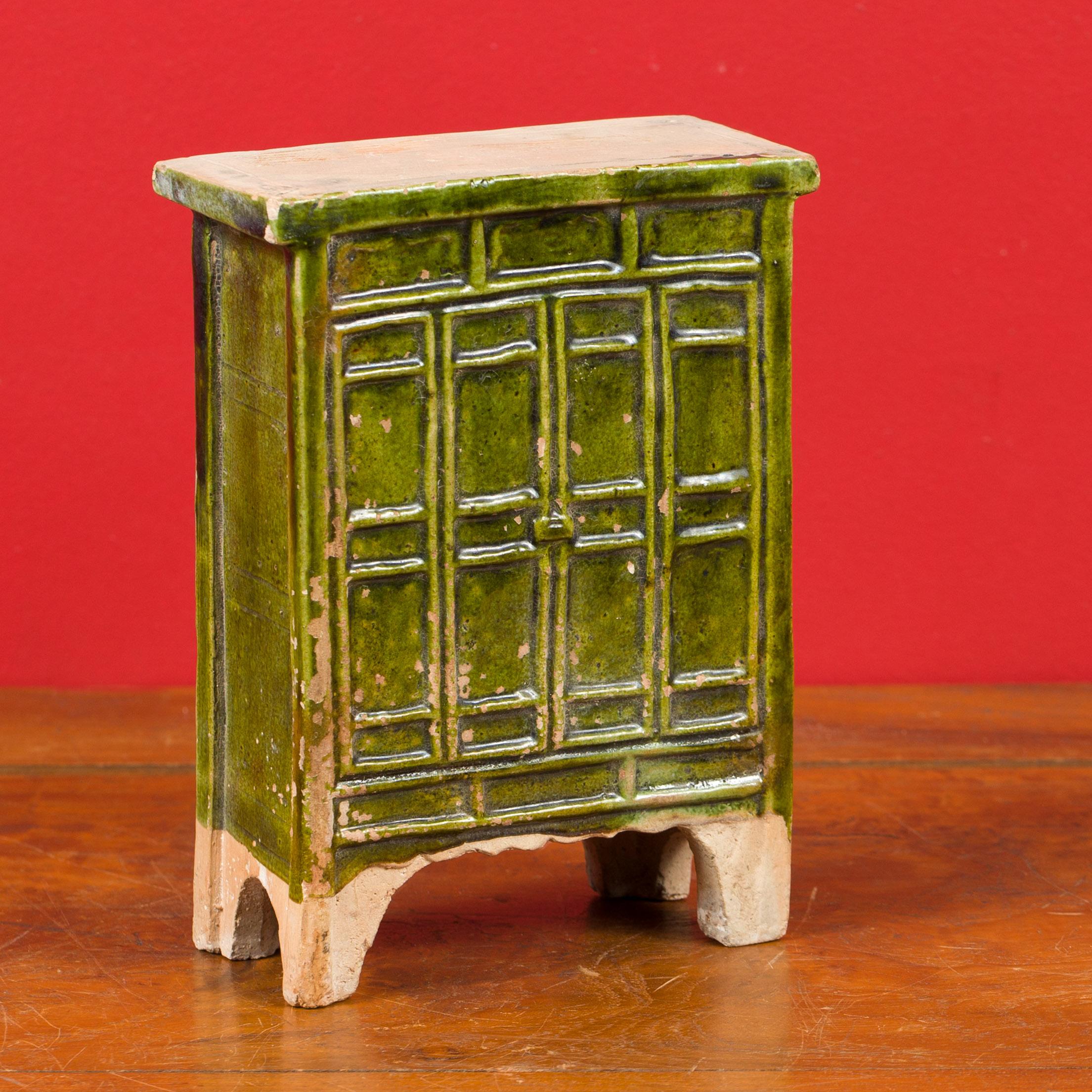 A Chinese Ming Dynasty period miniature terracotta armoire with green glazed finish and bracket feet. Created in China during the Ming Dynasty (1368 - 1644), this exquisite miniature terracotta armoire is a captivating example of historical