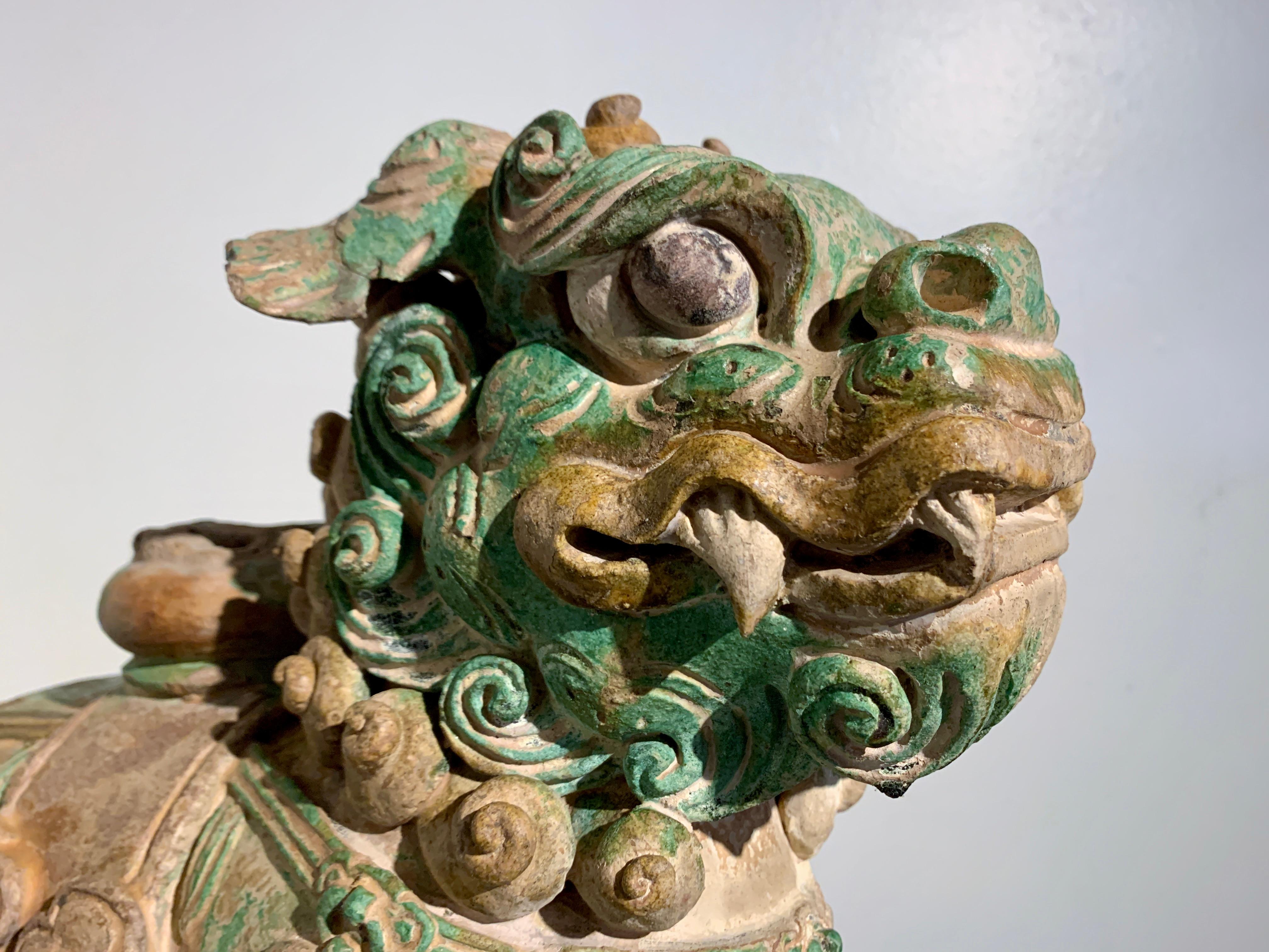 A fantastic Chinese sancai glazed tilework celestial guardian lion, late Ming Dynasty (1368 - 1644), circa late 16th century, China.

The charming and ferocious lion is portrayed in motion, striding forward upon a rectangular plinth. Its dragon-like