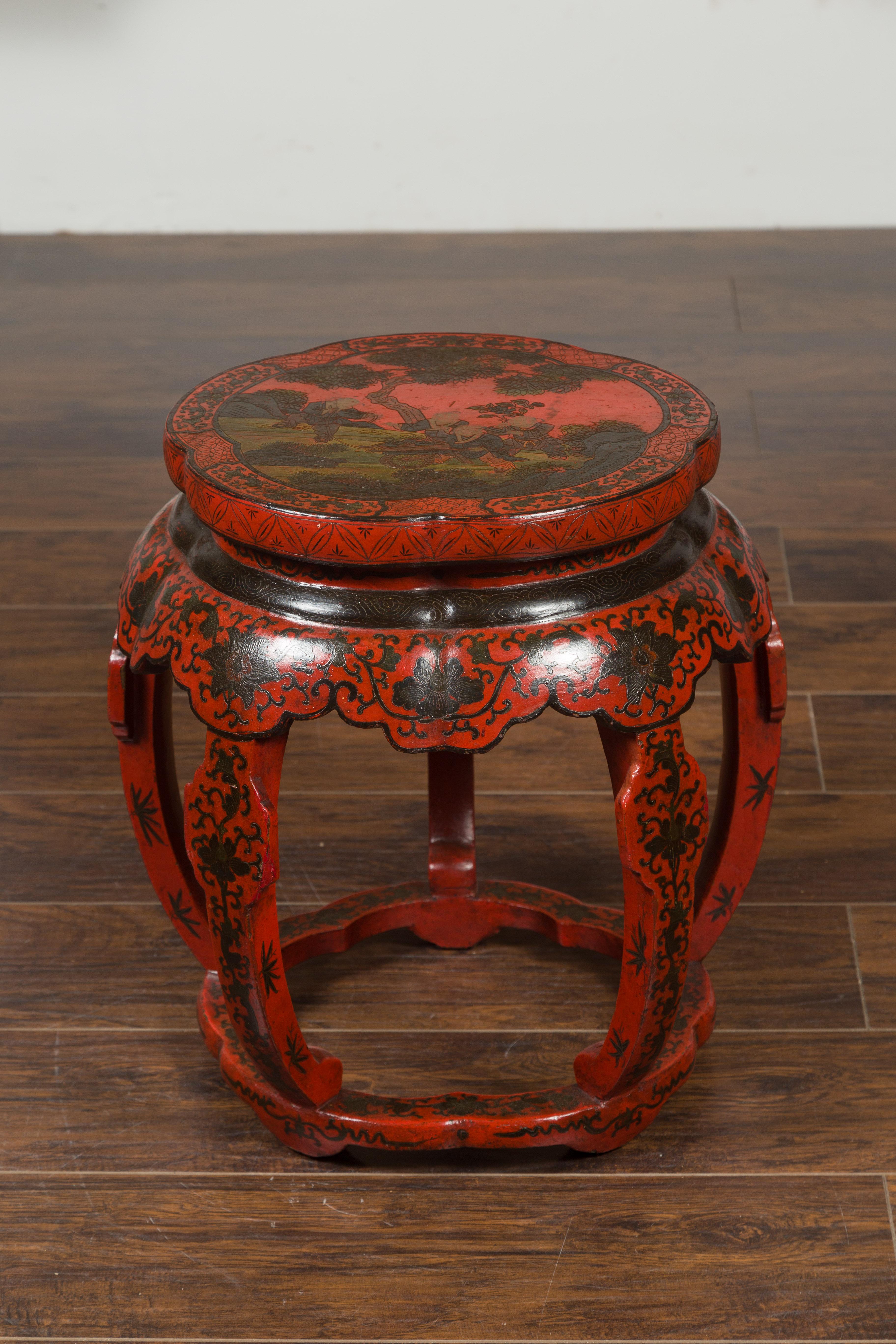 A Chinese Ming Dynasty style red and black lacquered drum stool from the early 20th century, with chinoiserie decor. Created in China during the first quarter of the 20th century, this Ming style drum stool will make for an excellent drinks table or