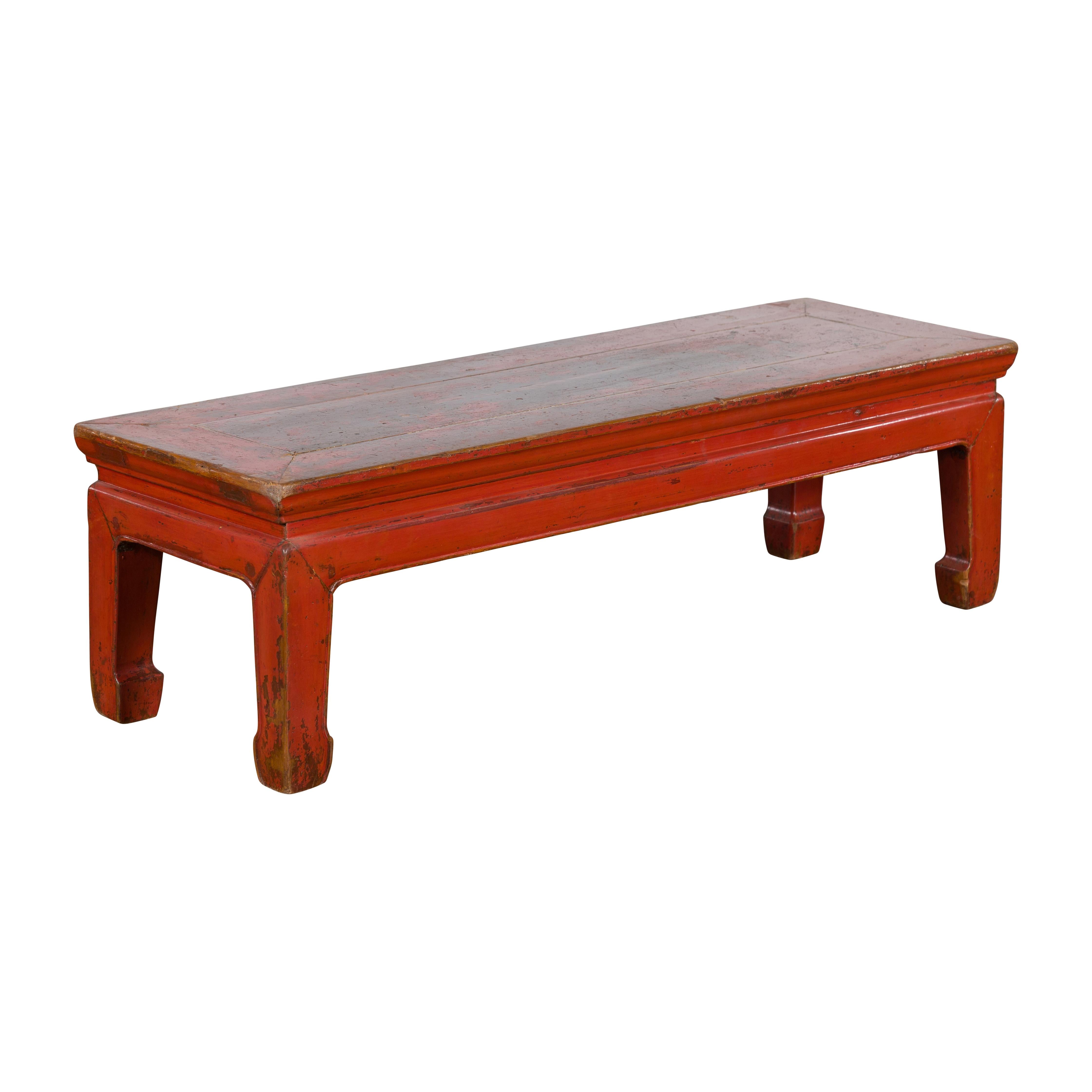 A Chinese Ming Dynasty style red lacquered low table from the early 20th century, with distressed finish and horse hoof legs. Created in China during the early years of the 20th century, this low Ming style table features a rectangular waisted top