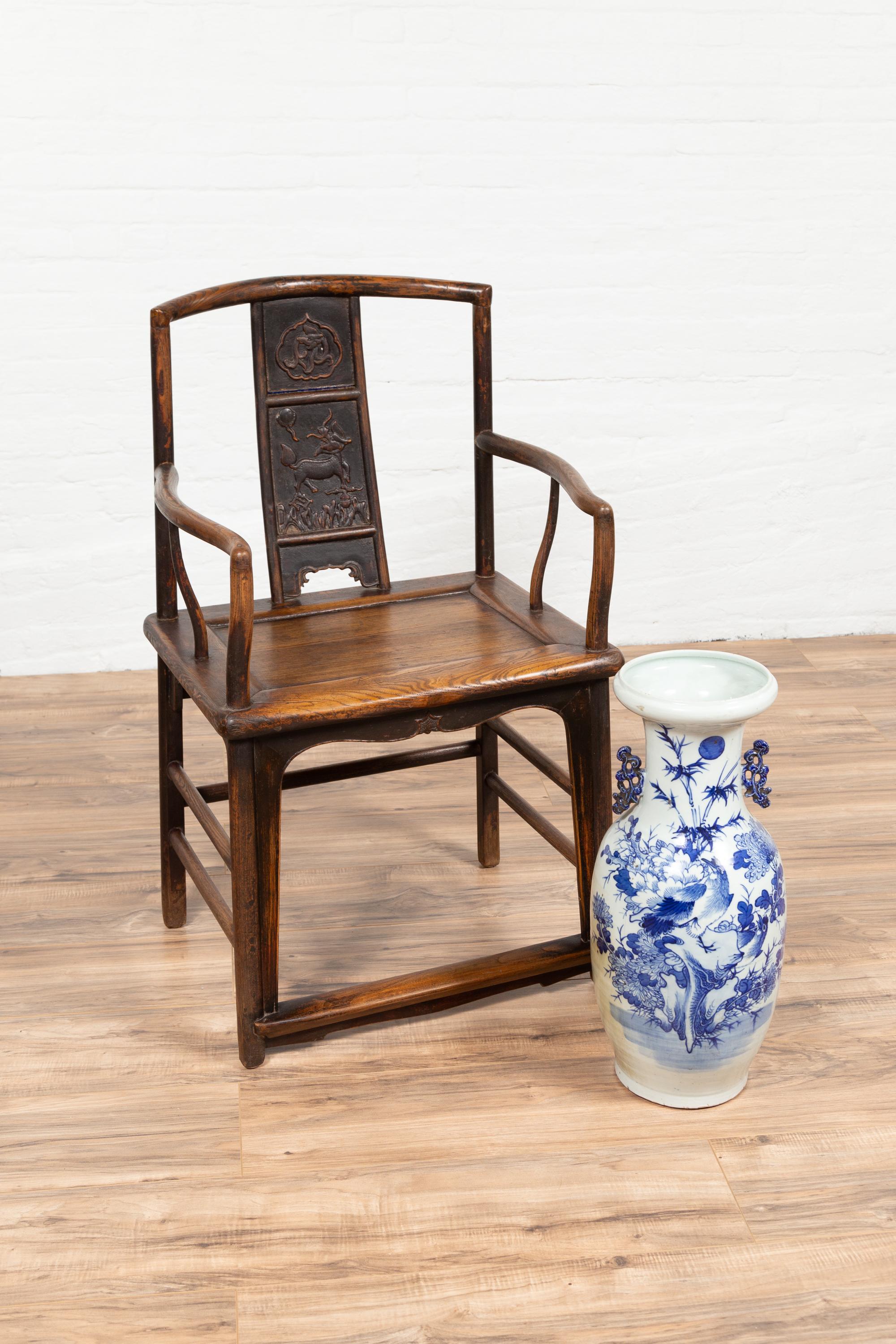 A Ming Dynasty style elmwood wedding chair from circa 1900, with carved panels on the splat, curved arms, and gooseneck front posts. This early 20th-century Ming Dynasty style wedding chair, crafted from elmwood, embodies the essence of traditional