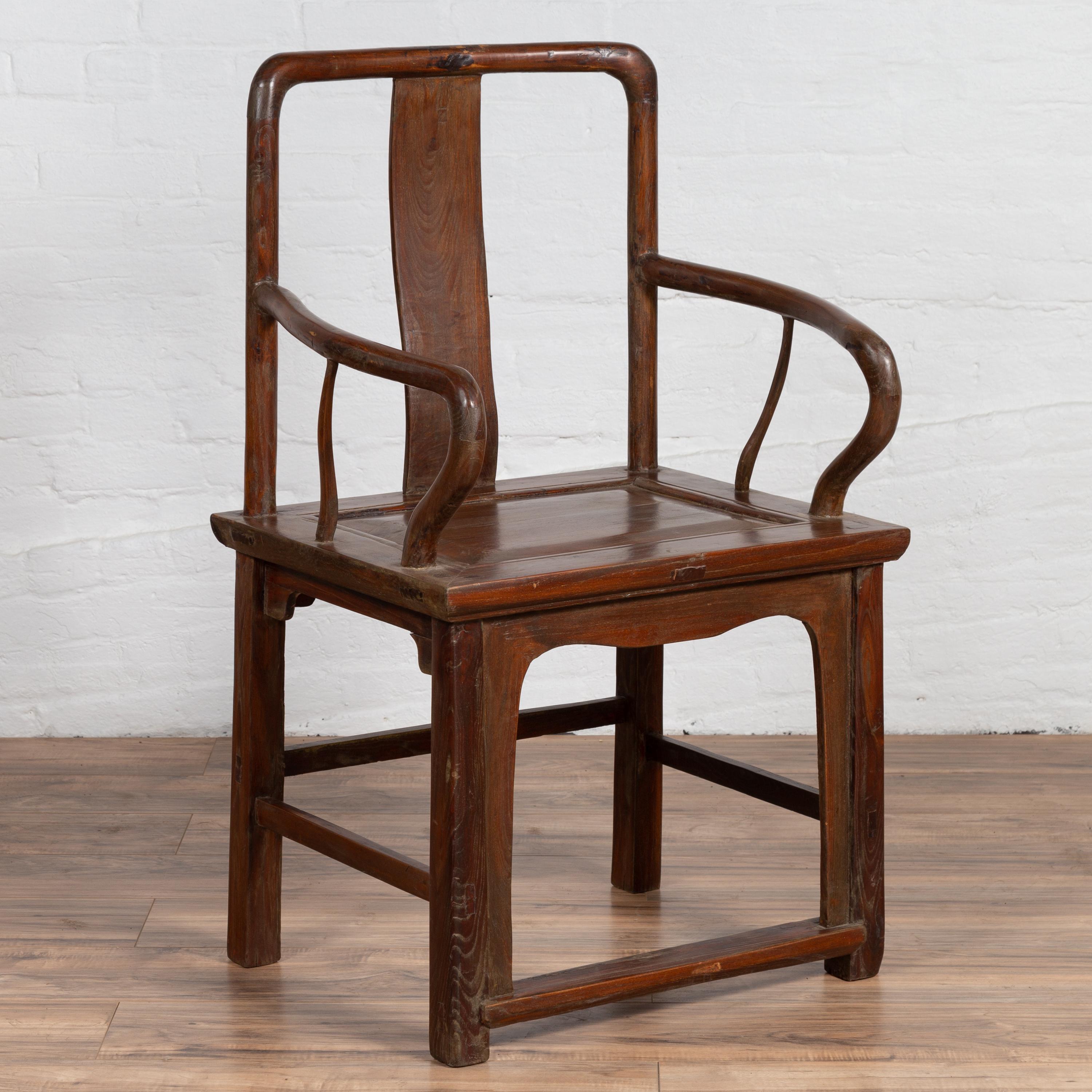 A Chinese antique Ming Dynasty style elmwood armchair from the early 20th century, with open back, central splat and curving armrests. Born in China during the early years of the 20th century, this exquisite armchair features an open back with