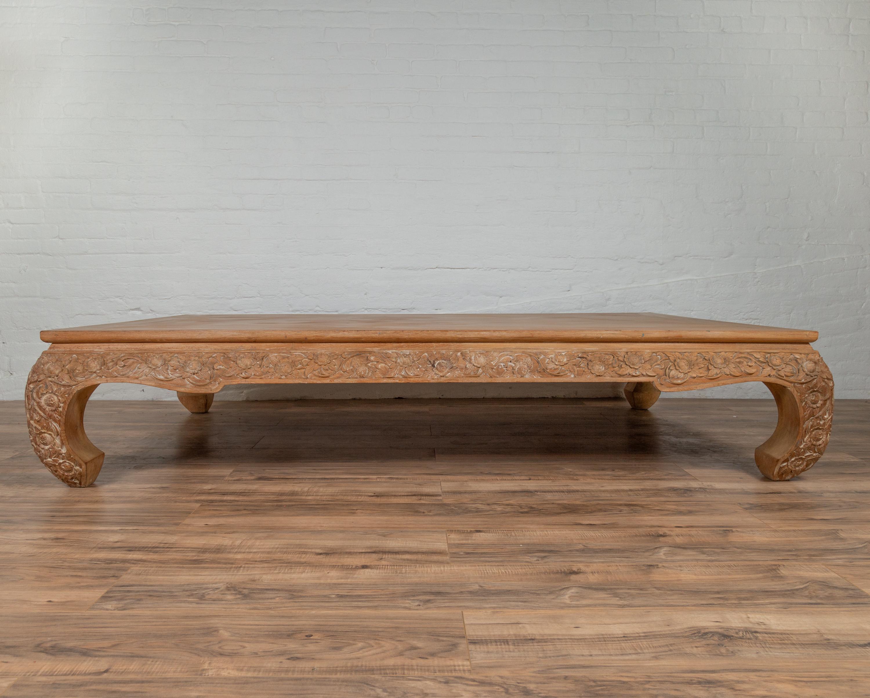 An antique Chinese Ming Dynasty style all natural teak coffee table with hand-carved floral décor and bulging legs. Originally used as a daybed, this Chinese Ming Dynasty style piece features a rectangular planked top sitting above a stunning base.