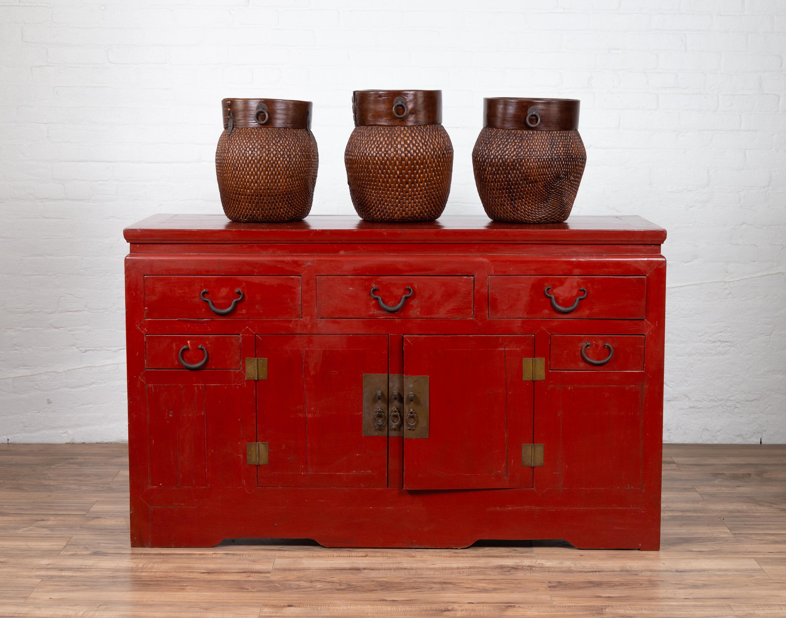 An antique Chinese Ming Dynasty style red lacquered console cabinet from the early 20th century, with five drawers and double doors. Born in China during the early years of the 20th century, this console cabinet captures our attention with its red