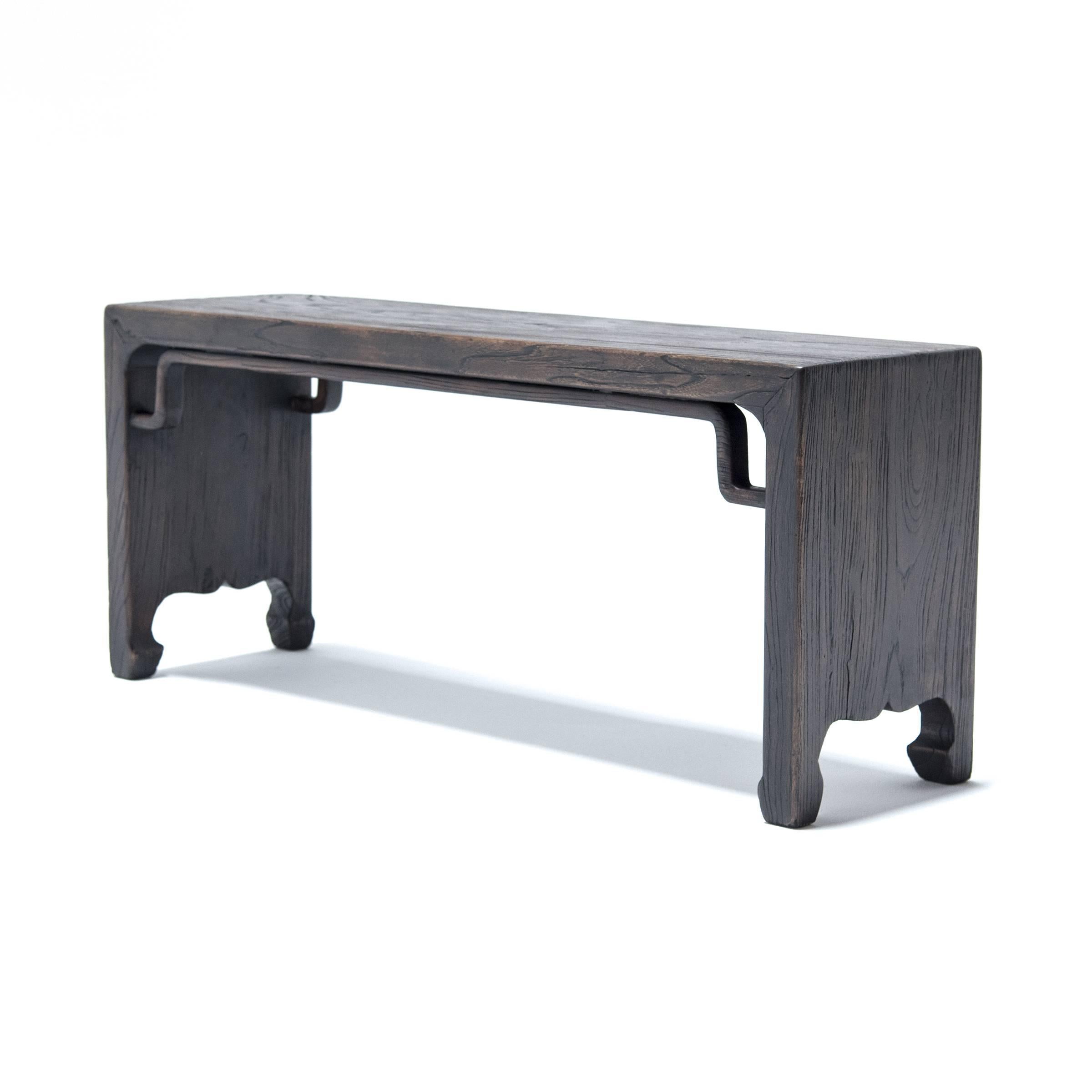 This waterfall bench with mitered corners is made from elm wood reclaimed from 18th century Northern Chinese buildings. It is a modern interpretation of traditional Ming form. The solid planks are finished on each side with carved, hoofed feet. The