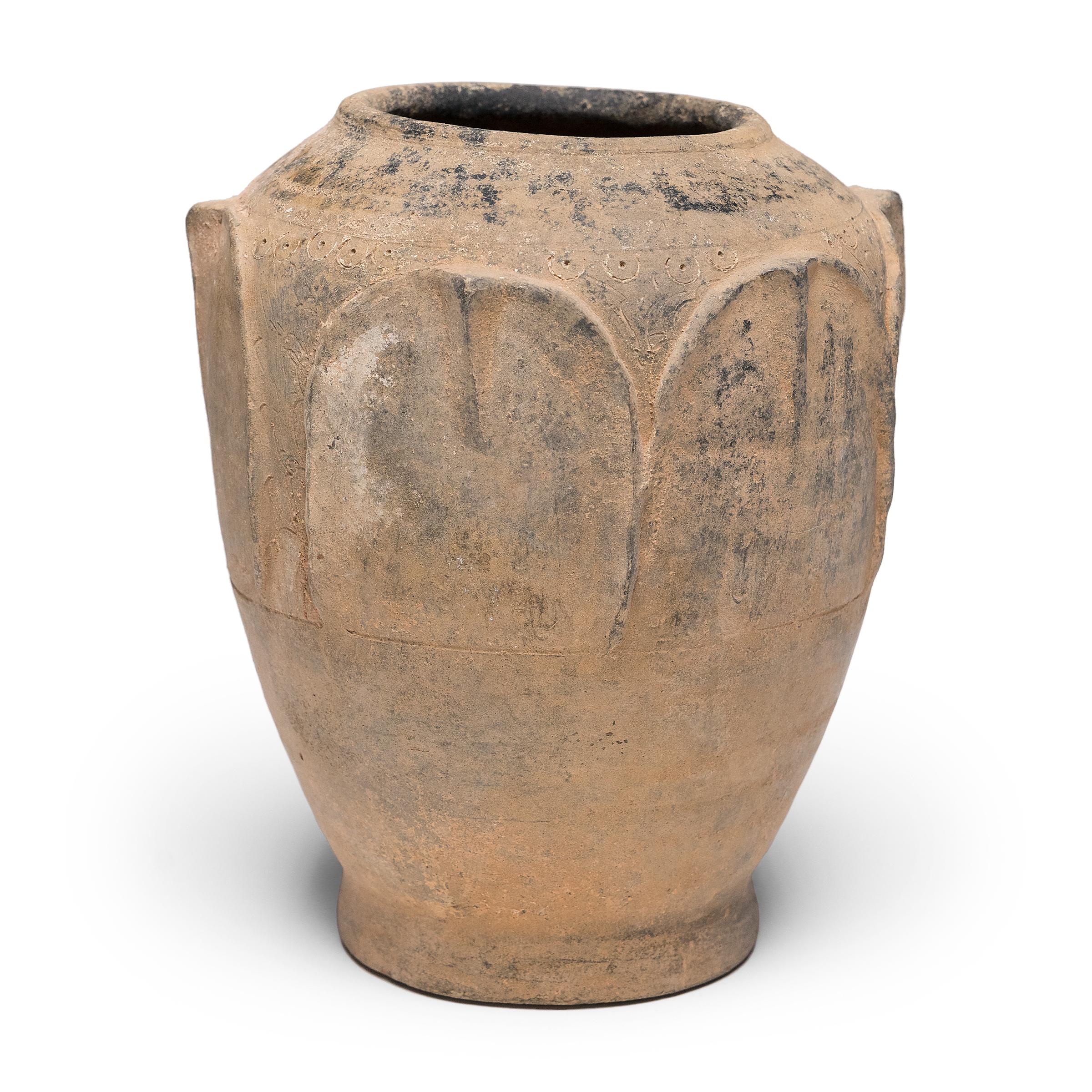 Mit ihrer ausgewogenen Silhouette und der gedämpften Farbpalette strahlt diese Lotosopfervase aus der frühen Ming-Dynastie (1368-1644) Ruhe und Raffinesse aus. Das vor Jahrhunderten in der Provinz Yunnan gefertigte Tongefäß war ursprünglich ein