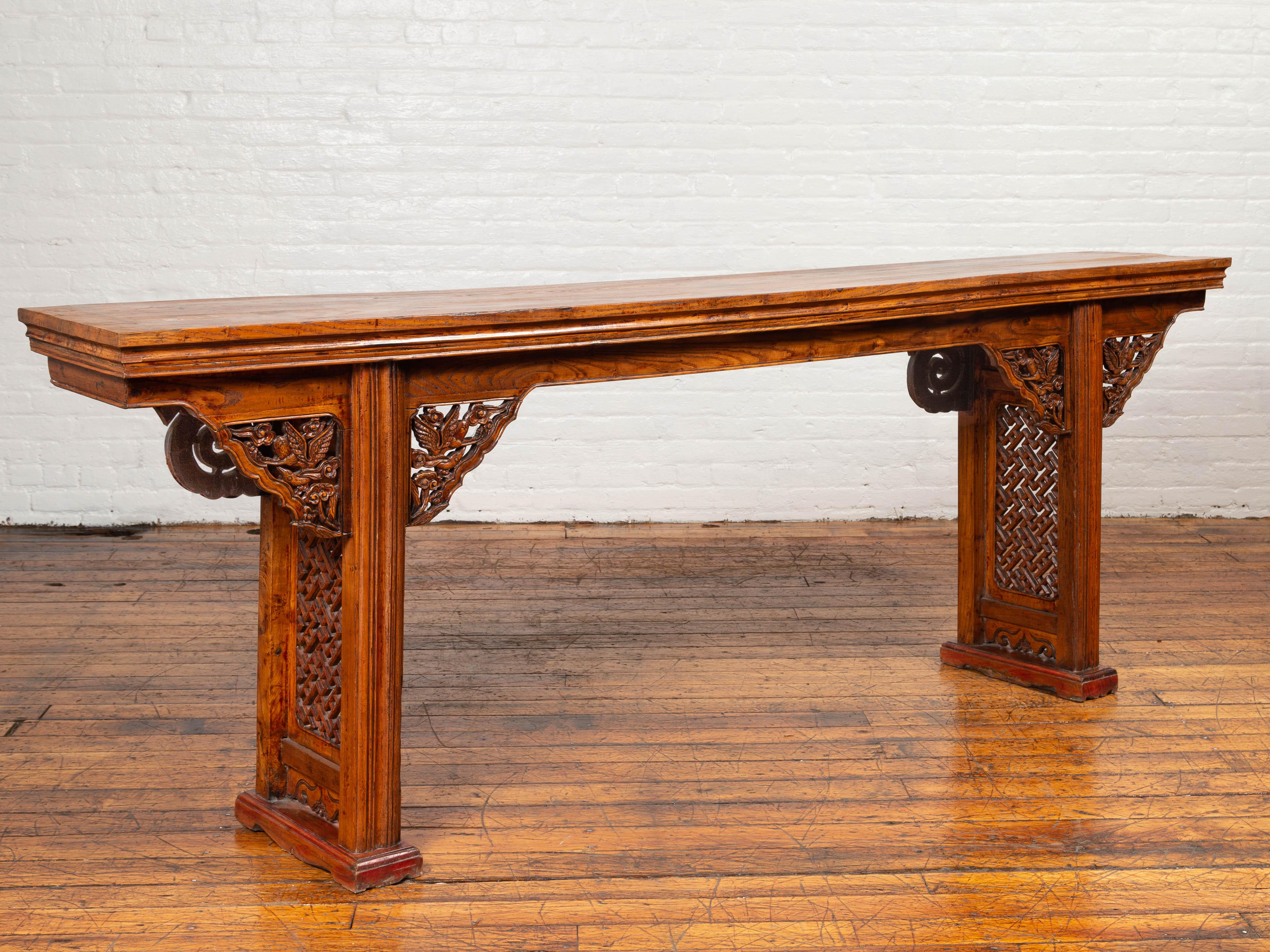 A Chinese Ming Dynasty style altar console table with carved spandrels and fretwork design. Attracting our attention with its elegant lines and skillfully carved décor, this Chinese Ming Dynasty style console altar table features a long and narrow