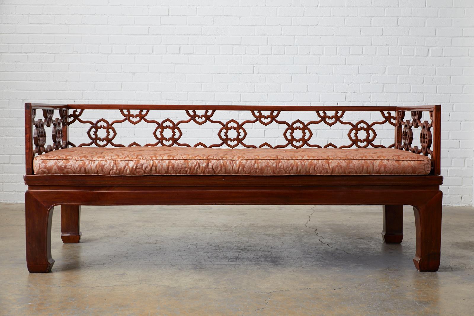 Remarkable Chinese carved hardwood daybed made in the Ming style with a grasscloth or raffia inset. The bed features beautifully hand carved back and sides with an open fretwork design and a floating quatrefoil link pattern. The firm grasscloth top