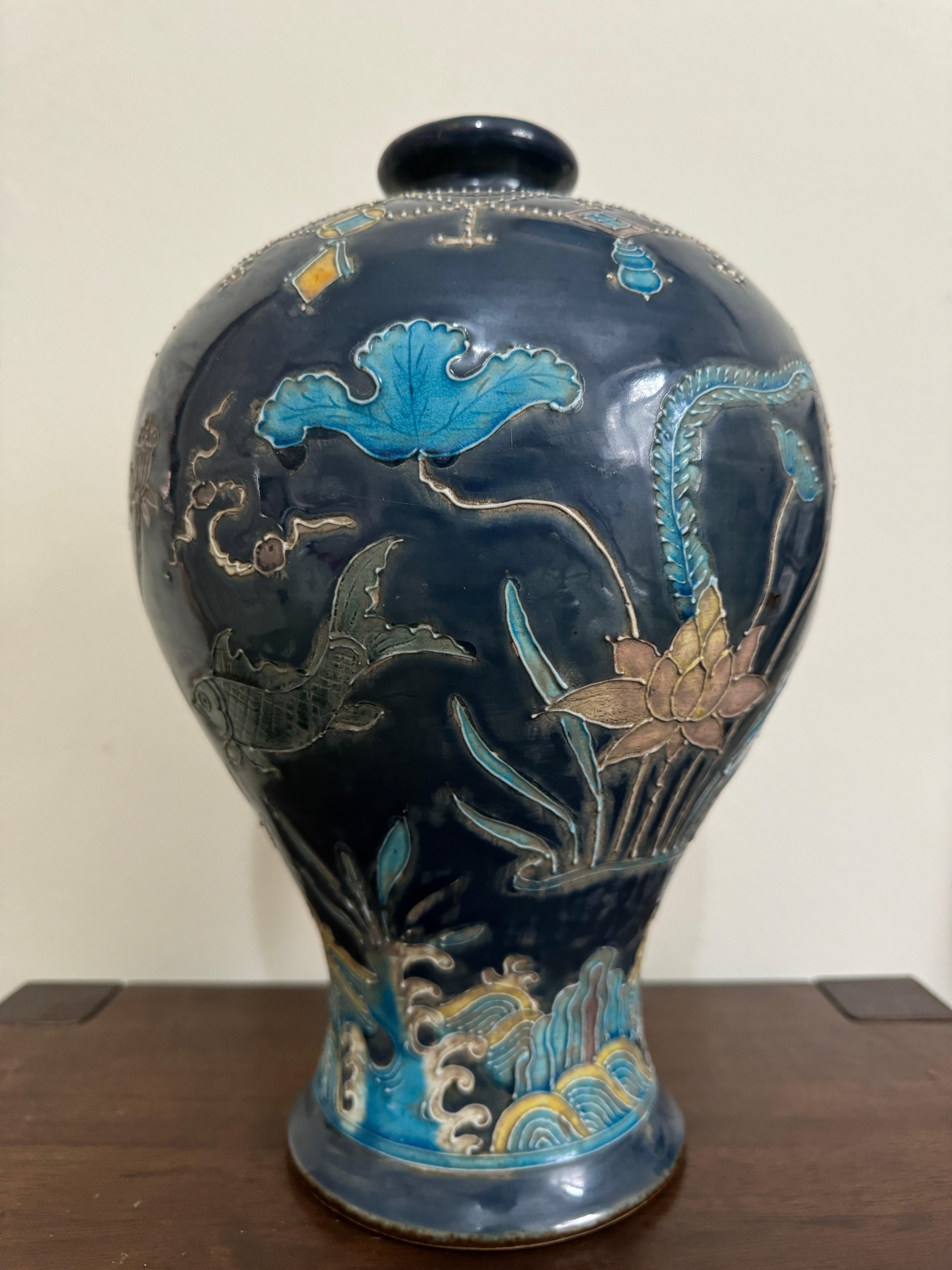 Chinese Ming Style Fahua Meiping Vase. The vase featuring raised lotus plants, carp and grasses emerging from waves, topped with a garland of beaded chains and precious objects around the shoulder. The design is outlined in slip and glazed in