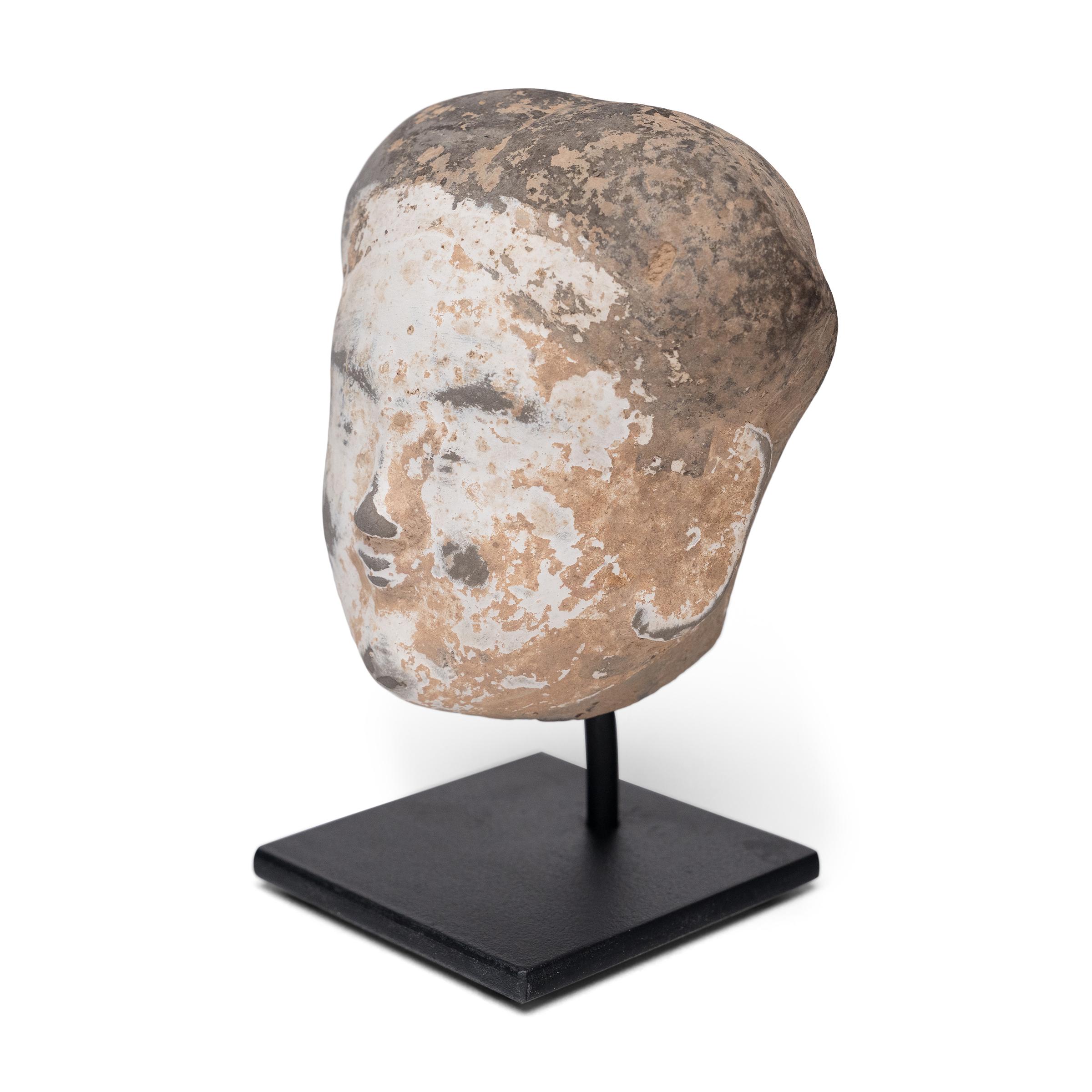 Questo piccolo busto in ceramica è la testa di un attendente personale della dinastia Han (206 a.C. - 220 d.C.). Un tipo di statuetta funeraria nota come míngqì, l'attendente sarebbe stato incluso nelle offerte funerarie per salutare e accompagnare