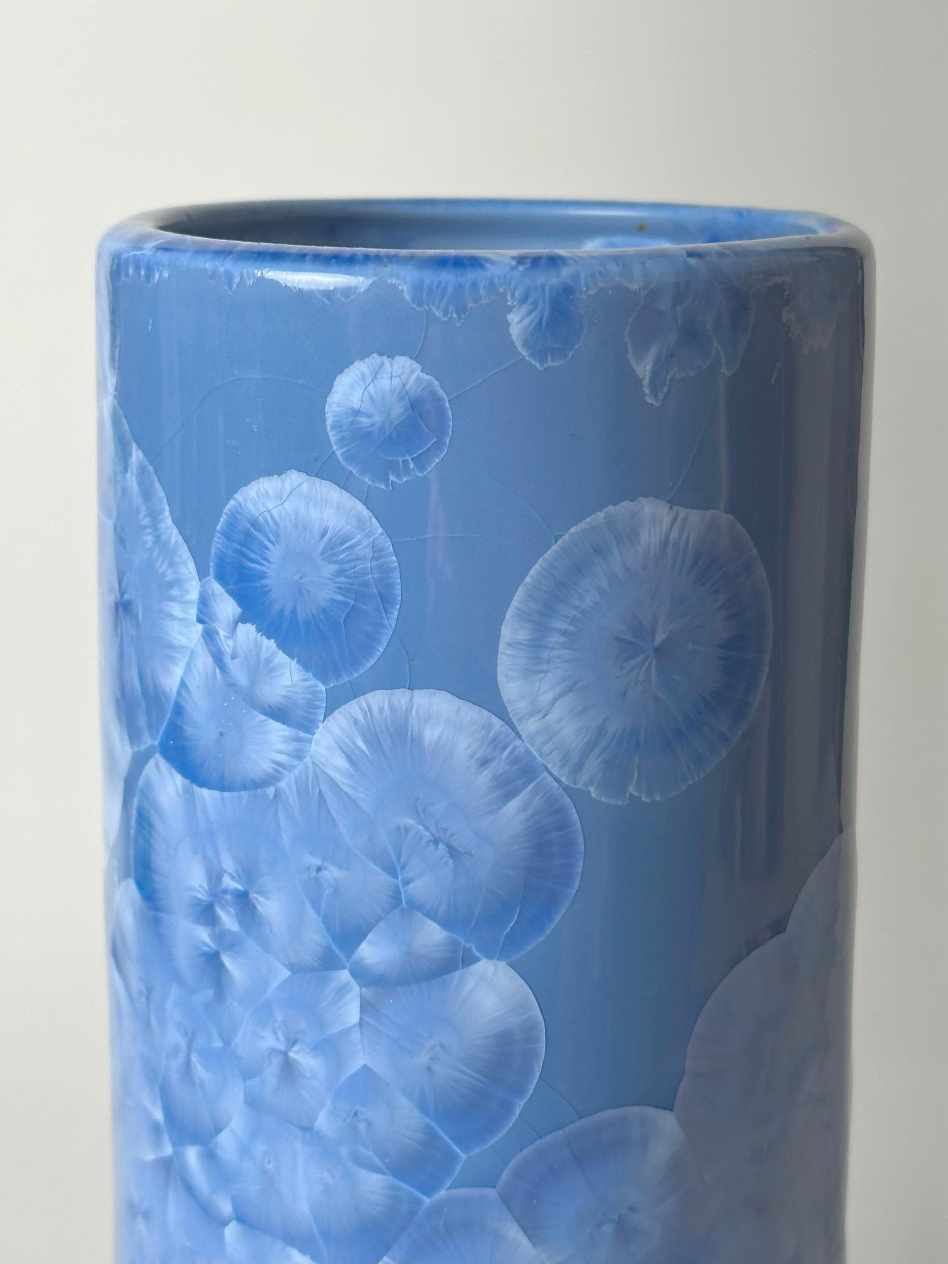Un grand vase cylindrique en porcelaine chinoise monochrome, fabriqué dans les années 1970 et recouvert d'une glaçure bleu bleuet raffinée. La forme verticale simple, souvent décrite comme un vase à déversement, est équilibrée et minimale,