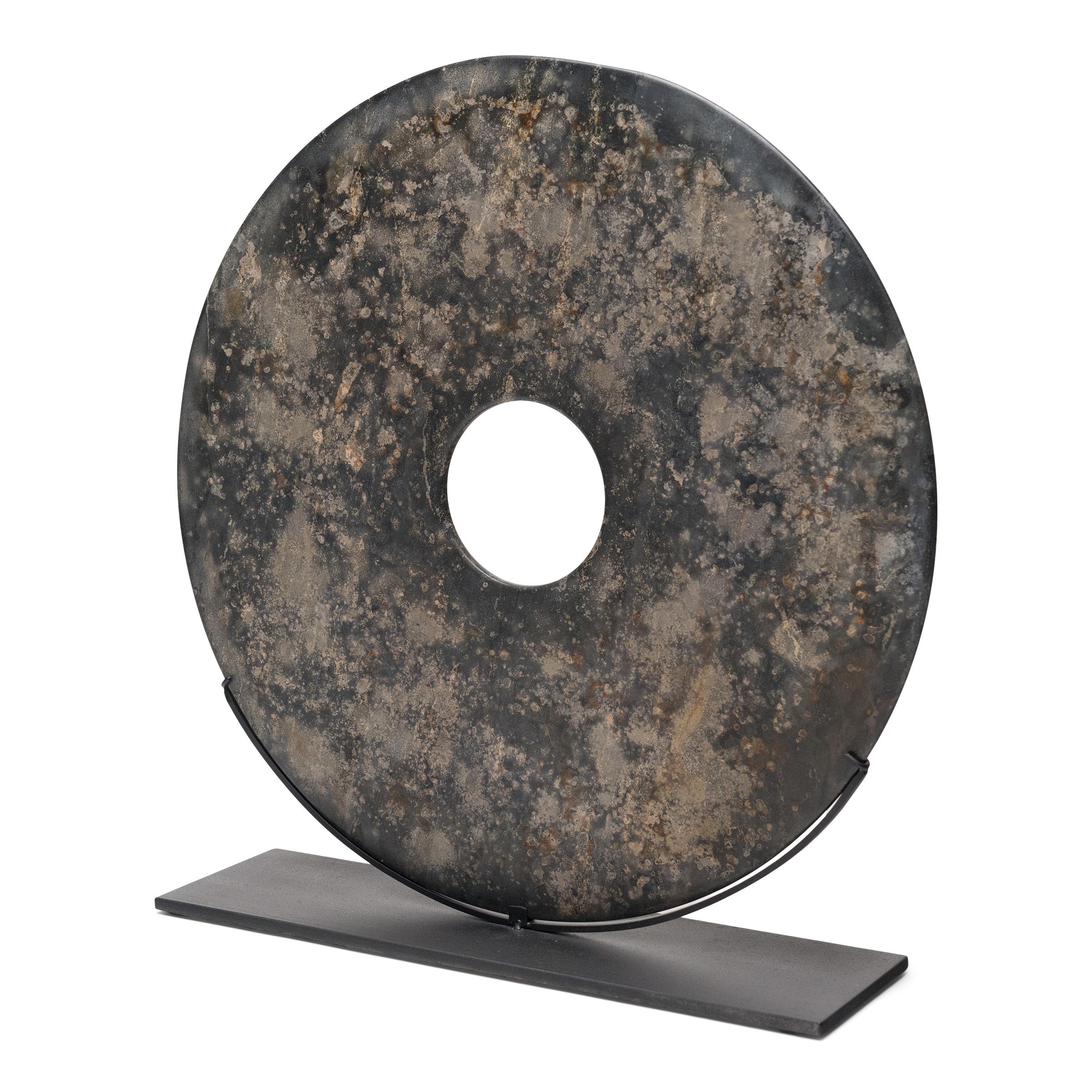 Found in the tombs of ancient Chinese emperors and aristocrats, bi discs such as this have a mysterious and spiritual history, and their function and significance remain uncertain. Thought to provide a conduit to the heavenly realm, bi discs are