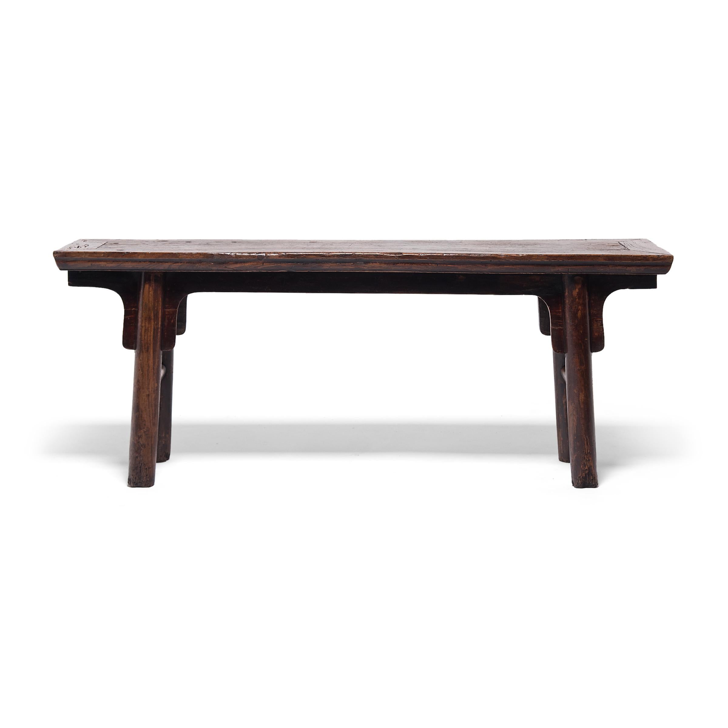 This elegant recessed-leg table dates to the early 19th century and was designed to be used as a surface for serving food or wine. The narrow table is designed in a classical Ming style, with a floating panel top, simple spandrels, and round legs