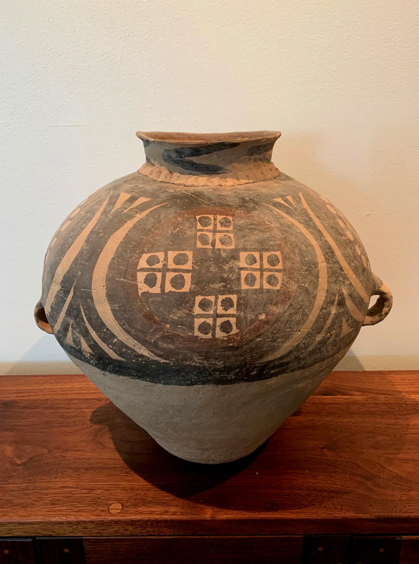 A large Chinese Neolithic funeral jar from Yangshao culture (5000-3000BC). The reddish earthen ware features a bulbous body, a short neck with a round opening and two jug ears on the side. It was hand built with coiling method which it can be felt