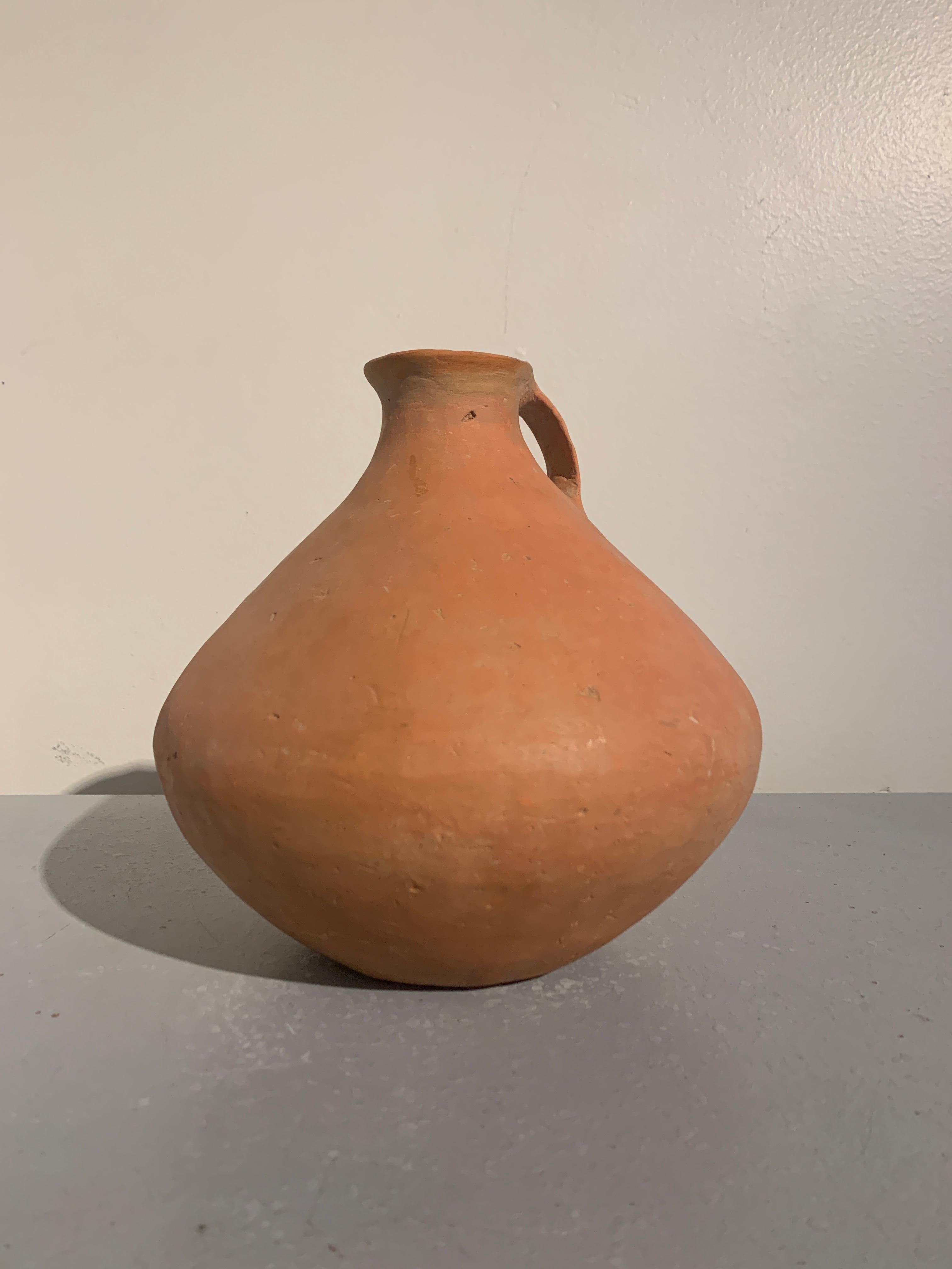 A sublime Chinese neolithic burnished red pottery jug, Qijia Culture (2200 BC - 1600 BC), modern day Gansu Province, China.

The simple jug of alluring form, with a voluptuous body, short, narrow neck with slightly everted mouth, and a single ear