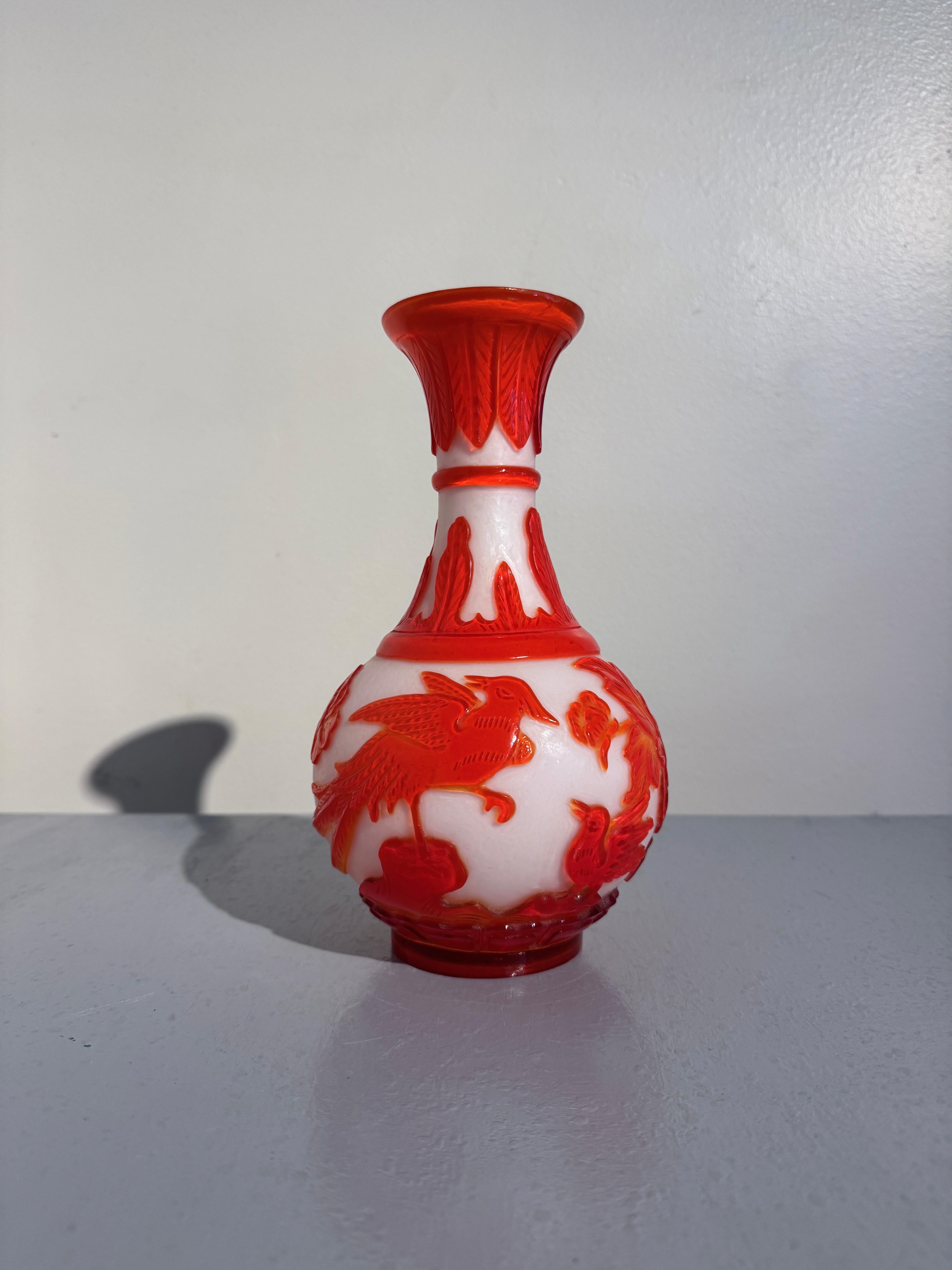 Magnifique vase piriforme en verre de Pékin sculpté en camée orange néon et blanc, vers les années 1960, Chine.

Vase poire en verre de Pékin de forme yuhuchunping, avec un corps bulbeux posé sur un pied court, un col haut et maigre, et une bouche