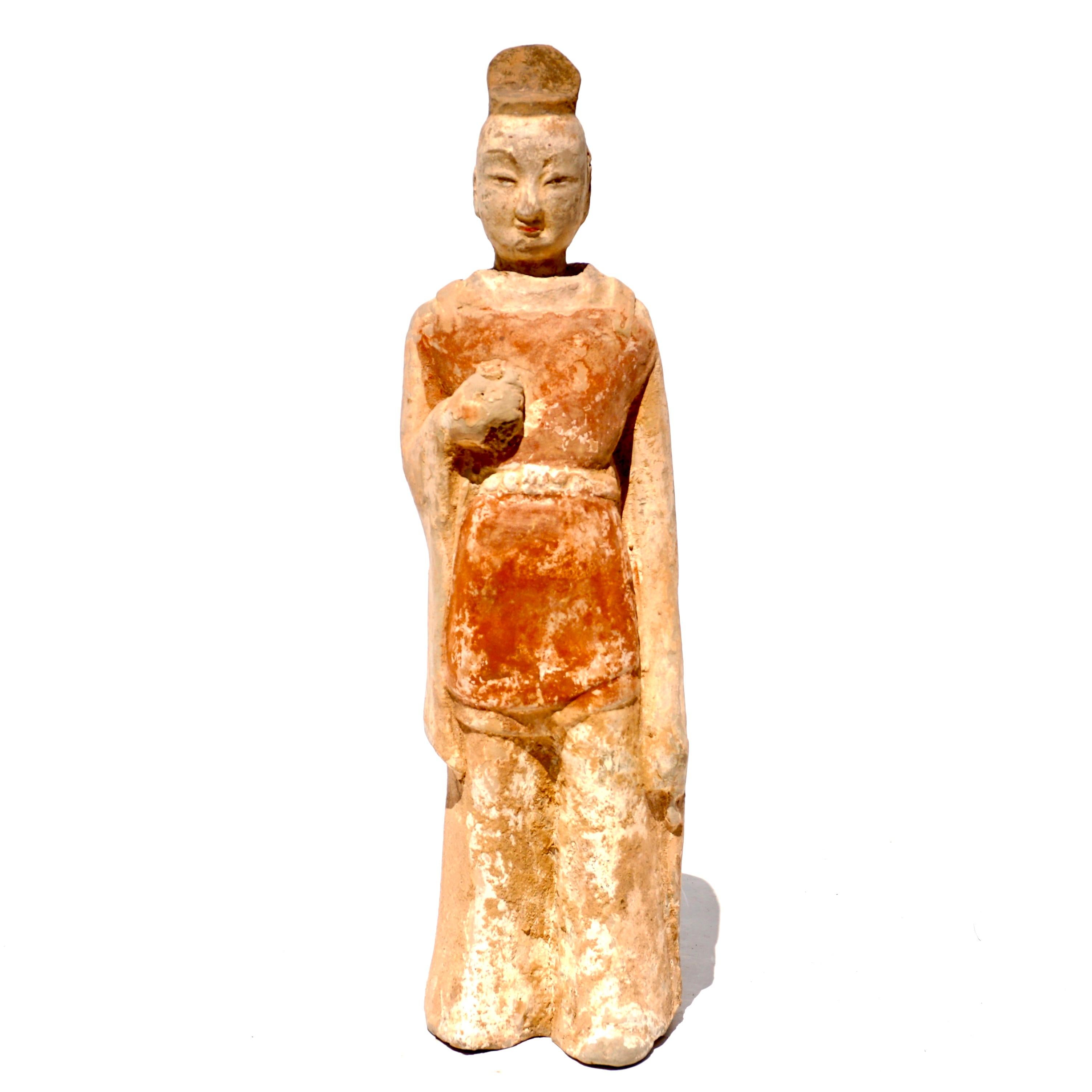 Circa 386-534 Statue de préposé en terre cuite de la Chine des Wei du Nord bien définie. 

Le personnage est représenté debout, les mains le long du corps, vêtu d'une robe rouge mi-longue à larges manches et d'un pantalon volumineux. Les figurines