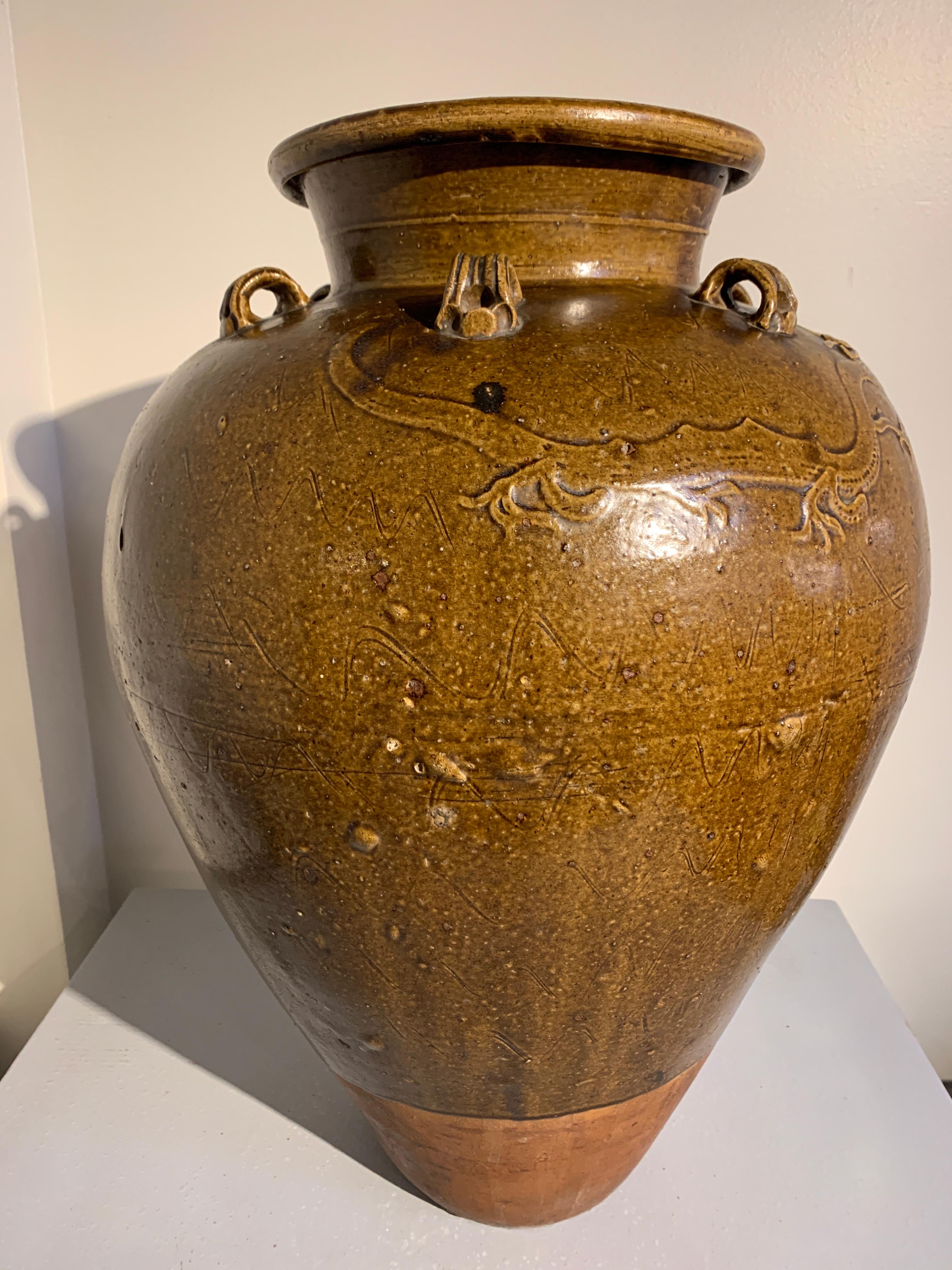 A fine and large Chinese brown ochre glazed stoneware storage jar, commonly known as a Martaban or Martavan jar, Ming dynasty, 15th-16th century.

The elegant ovoid jar with a slender body rising up from a narrow foot and terminating in a short