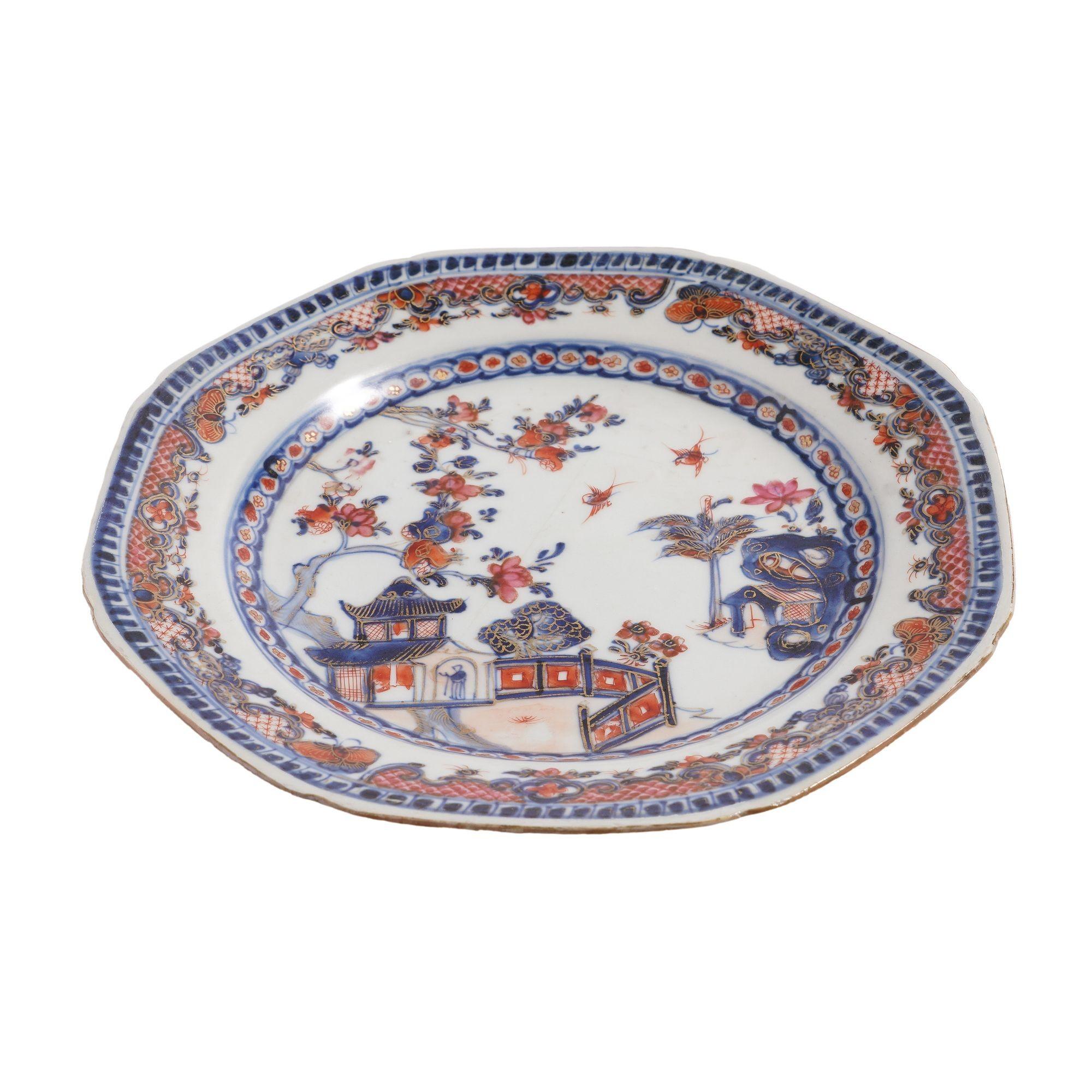 Chinese export porcelain octagonal plate decorated in the Chinese Imari taste. The plate is decorated in cobalt underglaze blue and oxide red with gilt highlights. The asymmetrical design of tea house in a garden is bordered with an inner band of