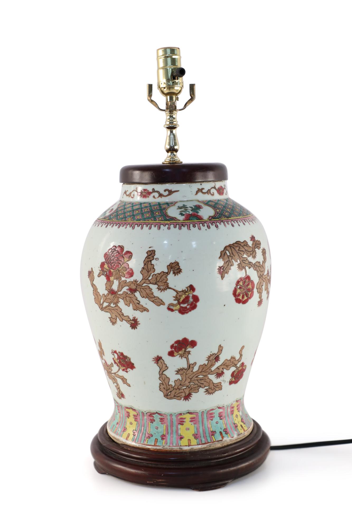 Chinese off-white porcelain table lamp made from a baluster-shaped vase decorated with a motif of beige foliage punctuated by red florals and two colorful geometric bands, a wooden base and brass hardware.