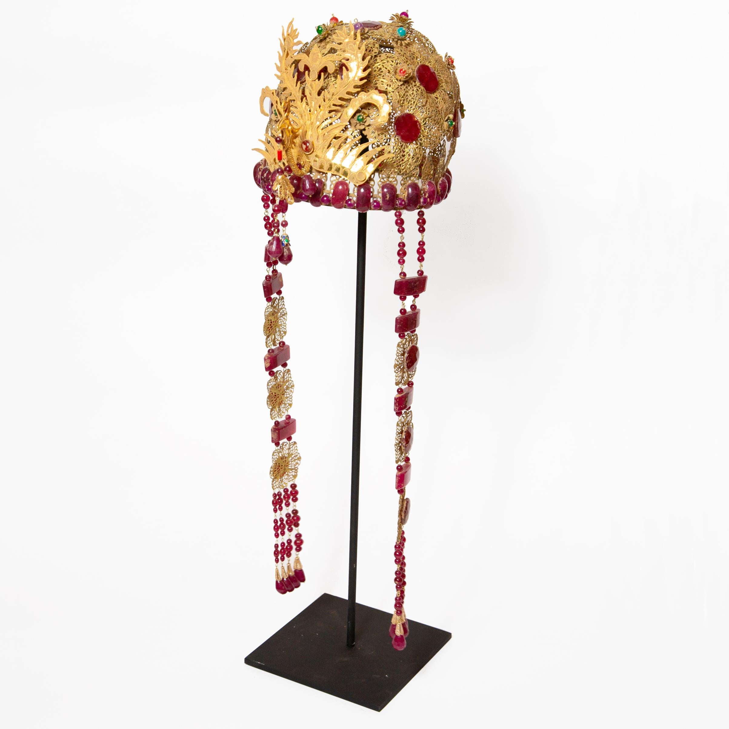 Chinese opera theatre headdress, ruby stone. Chinese opera theatre headdress with ornate gold flowers, dangling tassels, and rooster. Mid-20th century, mounted on a custom black painted metal base. Size: 25
