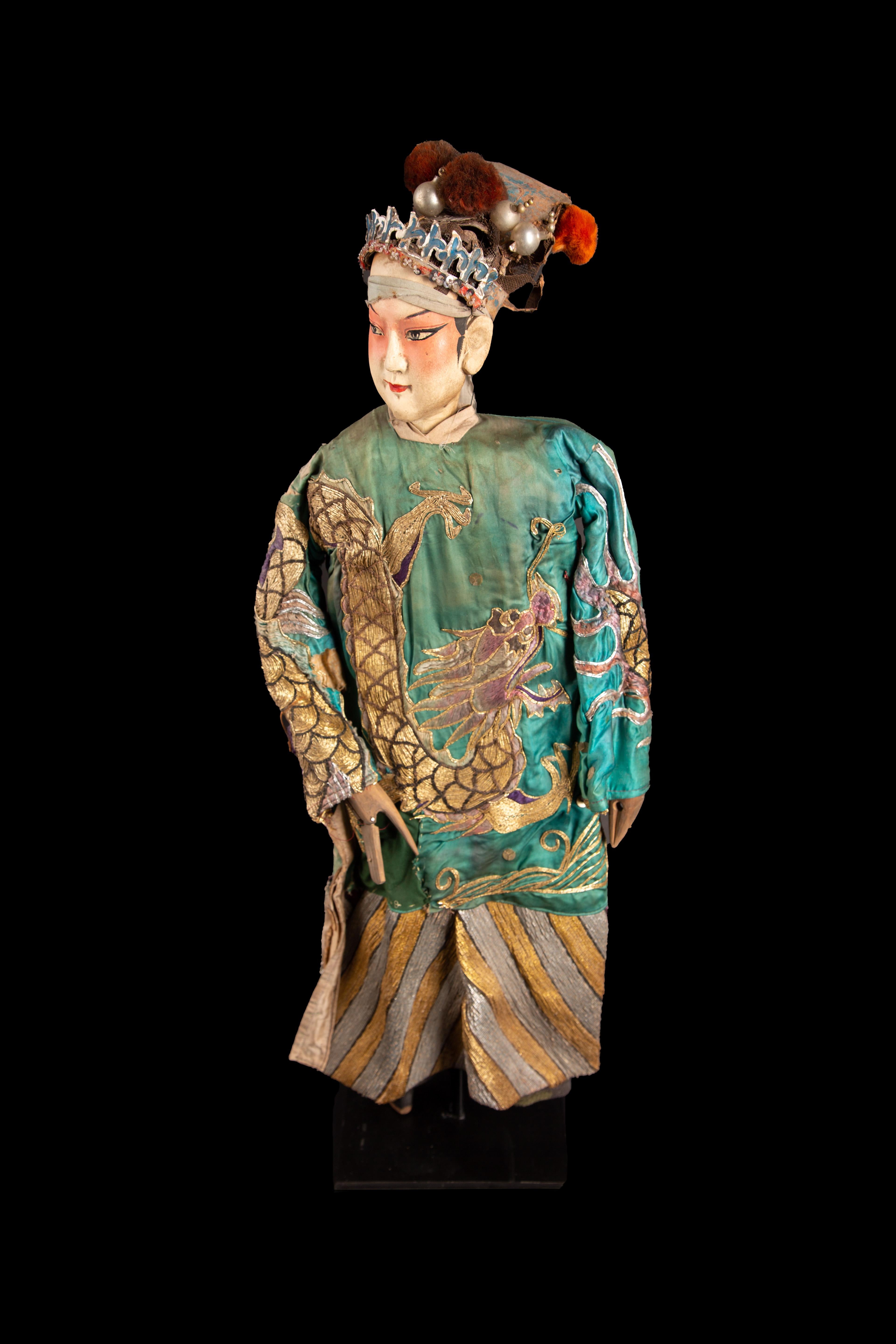 Chinese opera marionette male doll, circa 1920s. The head of this puppet is carved in a soft wood; the feet and hands are also made of wood. The hands can form a closed fist or an open palm by the joint at the level of the fingers. The headdress of