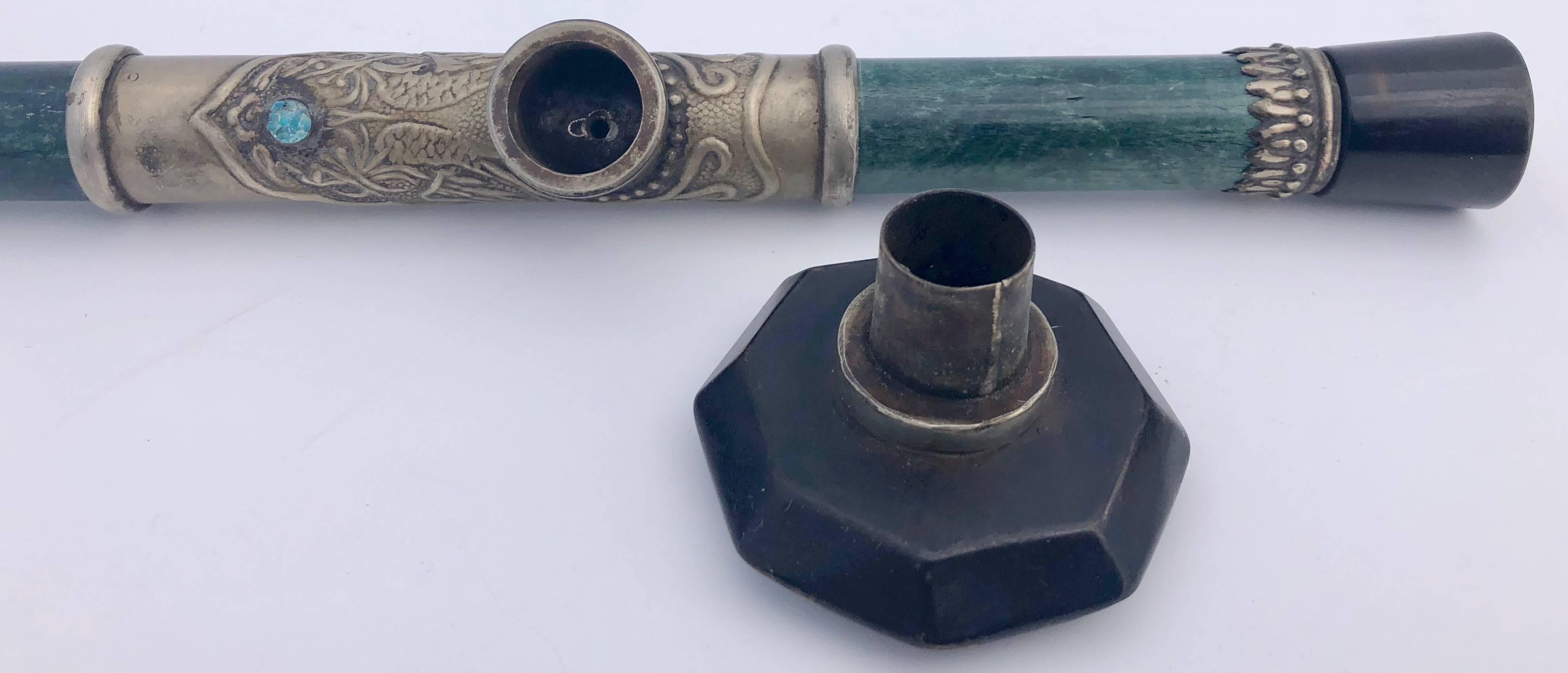 This beautiful Chinese jade opium pipe is from the 1700s. It has silver ring accents and a silver saddle. The bowl is hard stone as is the mouthpiece and cap. It is a lovely object to add to any collection.

Opium smoking began as a privilege of