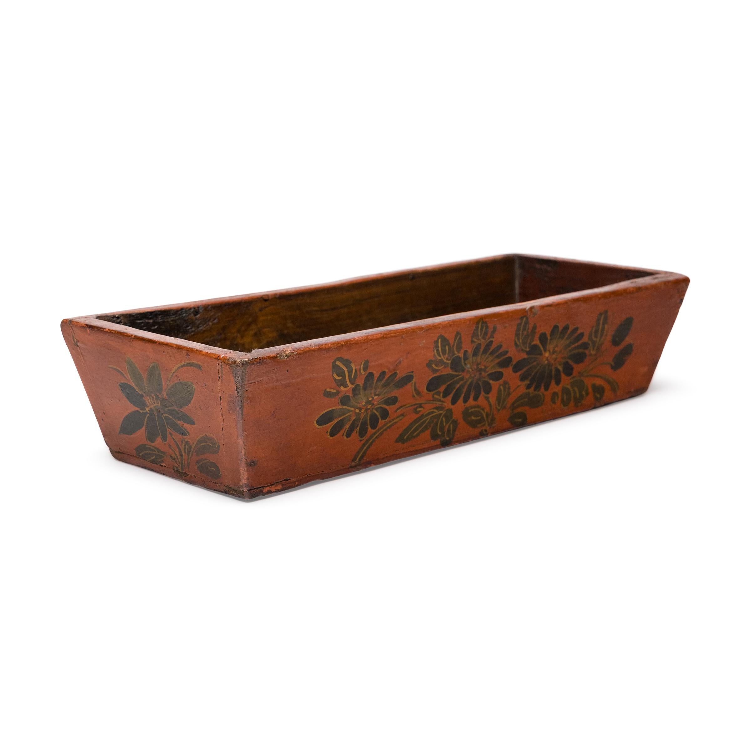 This provincial Chinese tray charms with vibrant orange lacquer and hand-brushed paintings of autumn flowers. Dated to the mid-20th century, the small folk tray is crafted of pine to a rectangular shape with flared sides. The long sides of the tray