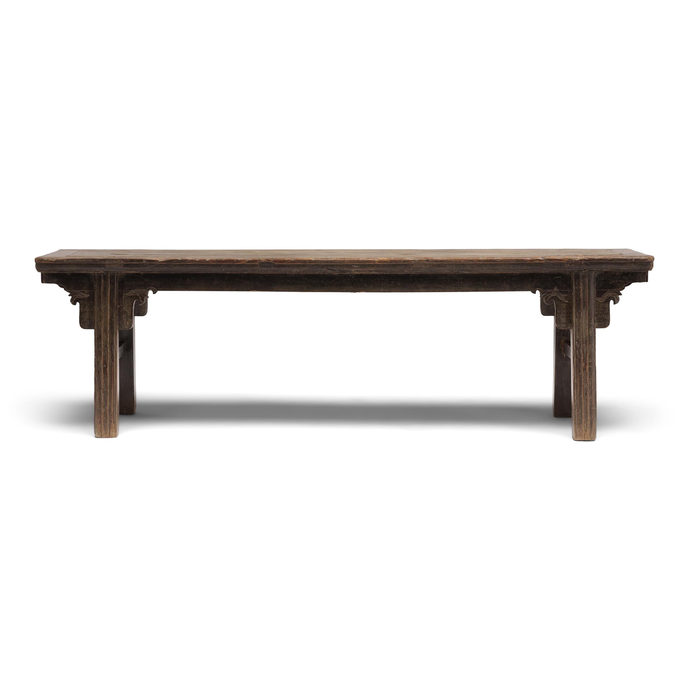 Cet élégant banc de la province chinoise de Shanxi suit la forme classique des pieds encastrés, définis par des pieds en retrait du bord supérieur et légèrement évasés pour plus de stabilité. Fabriqué en orme et assemblé par tenons et mortaises, cet