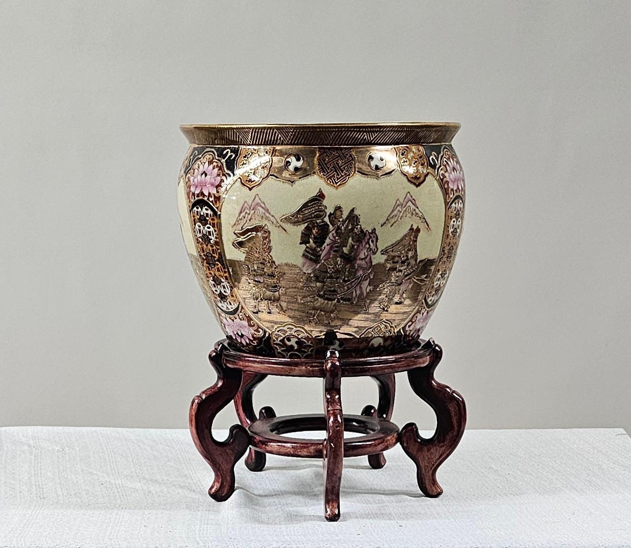 The Chinese ceramic fish bowl, jardiniere, or planter  features a rich, multicolored palette that vividly brings to life intricate scenes of regal procession, flanked by mountainous landscapes, warriors on horses and bordered by elaborate motifs of