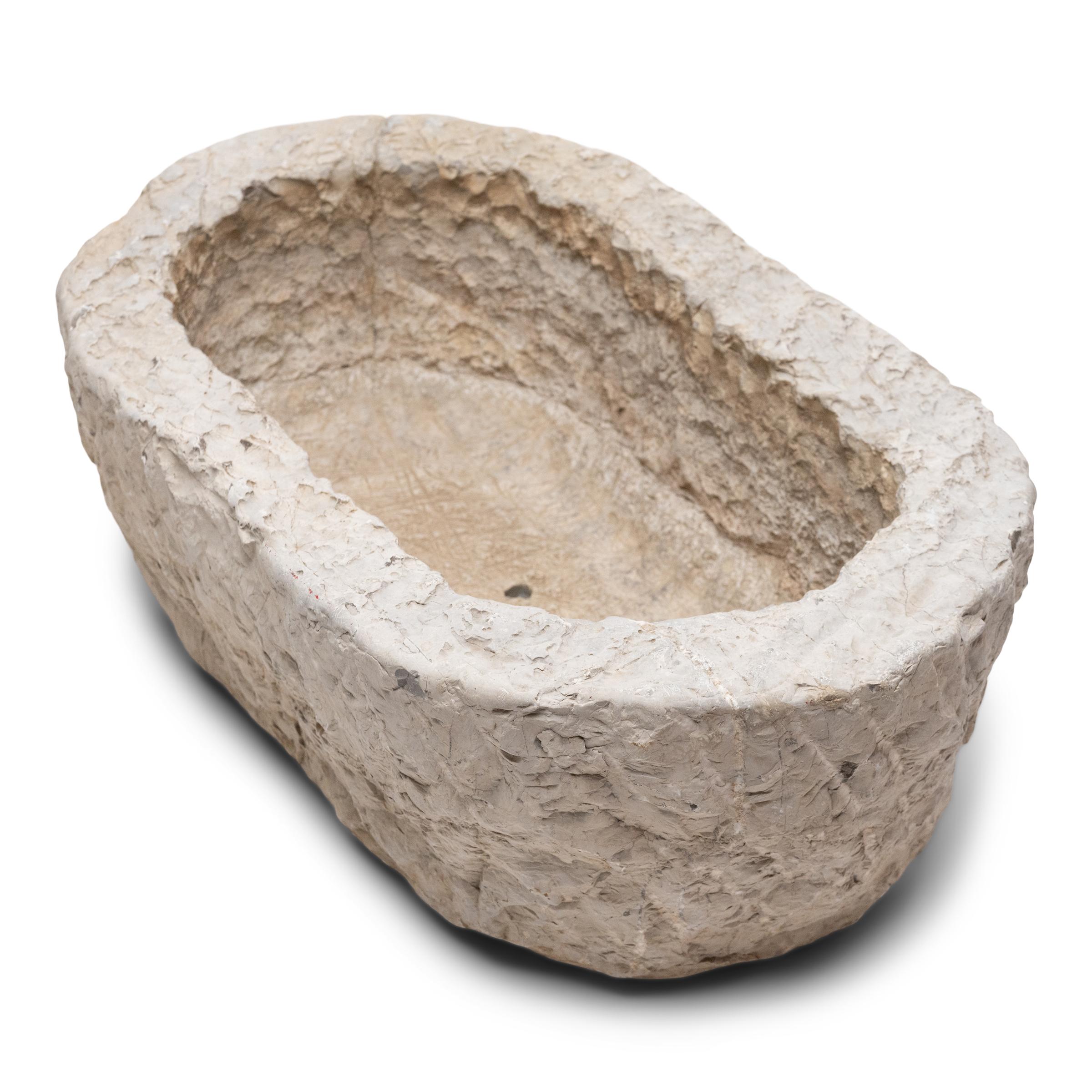 A rustic stone trough such as this was once a common sight in courtyards throughout rural China, filled with grain or water for chickens and other barnyard fowl. Chiseled from a block of limestone over a century ago, the stone vessel is sculpted to