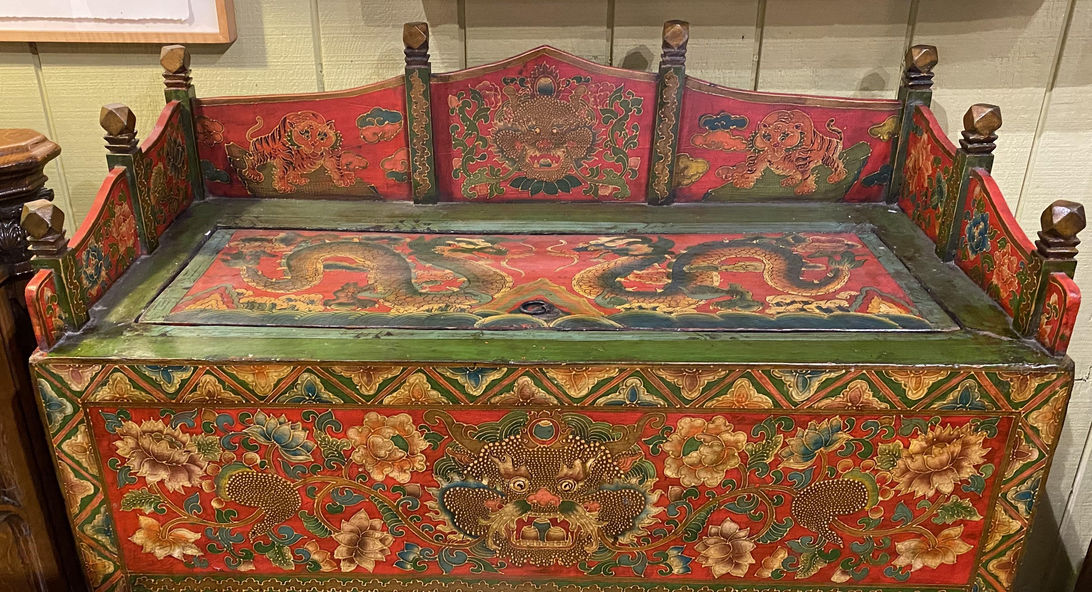 A beautiful polychrome decorated Chinese cabinet with paneled wooden gallery with carved finial posts and hinged lid, opening to two upper storage compartments, over a case with two doors, opening to a single lower storage area. The cabinet features