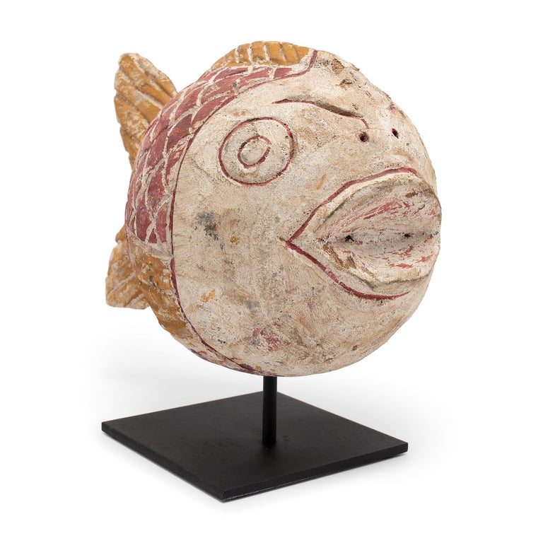 Hand-carved from reclaimed wood, this rustic fish sculpture recreates early 20th-century Chinese folk art designs. The fish is carved with a squat, rounded body and brightly painted with reds and yellows. Common motifs in Chinese art, fish are