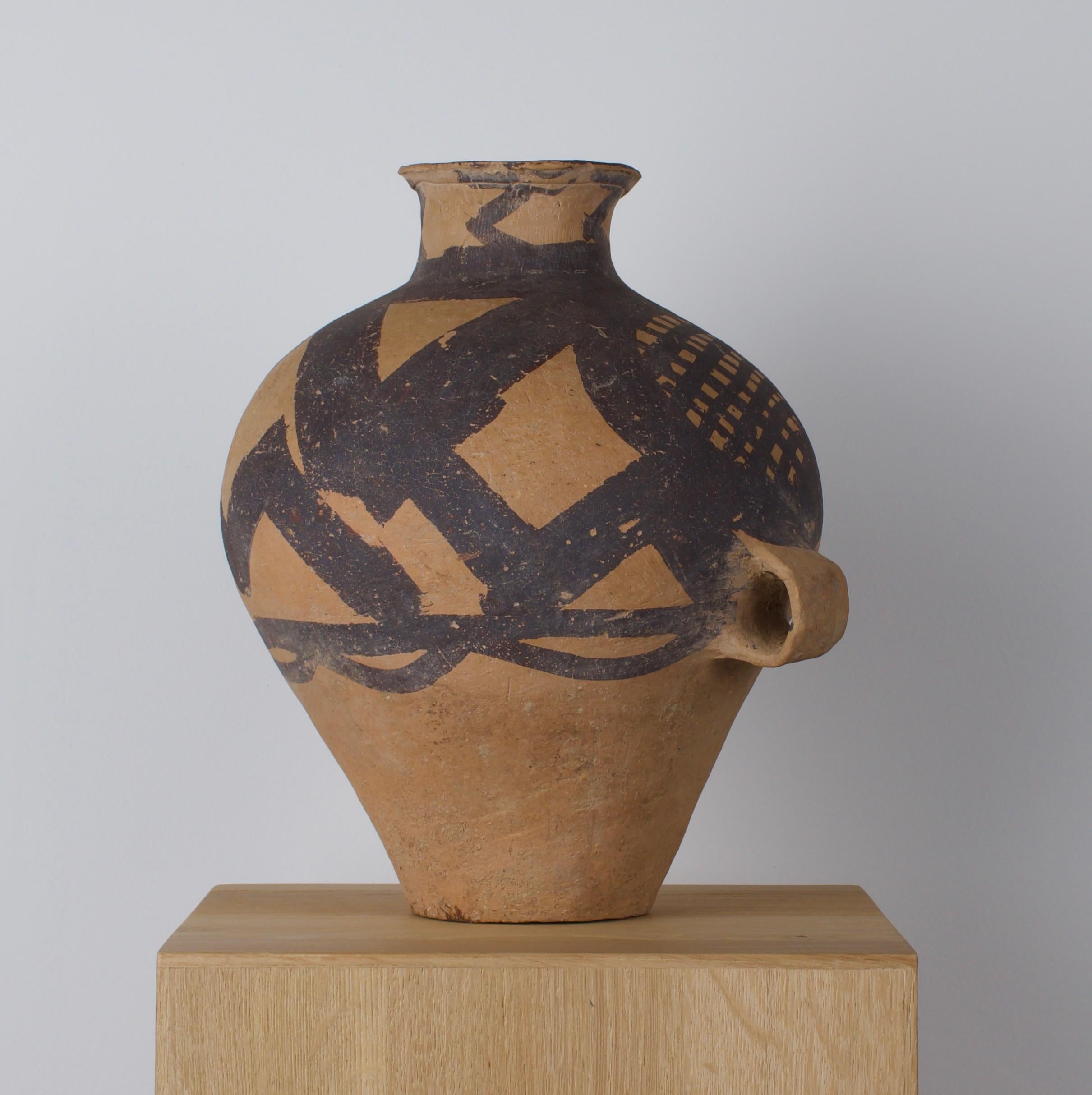 A beautiful jar of piriform body, waisted neck, everted rim and integral rectangular-section with loop handles, circumferential bands of painted geometric motifs of hatched circles, chevrons and hands. This historically significant artifact, where