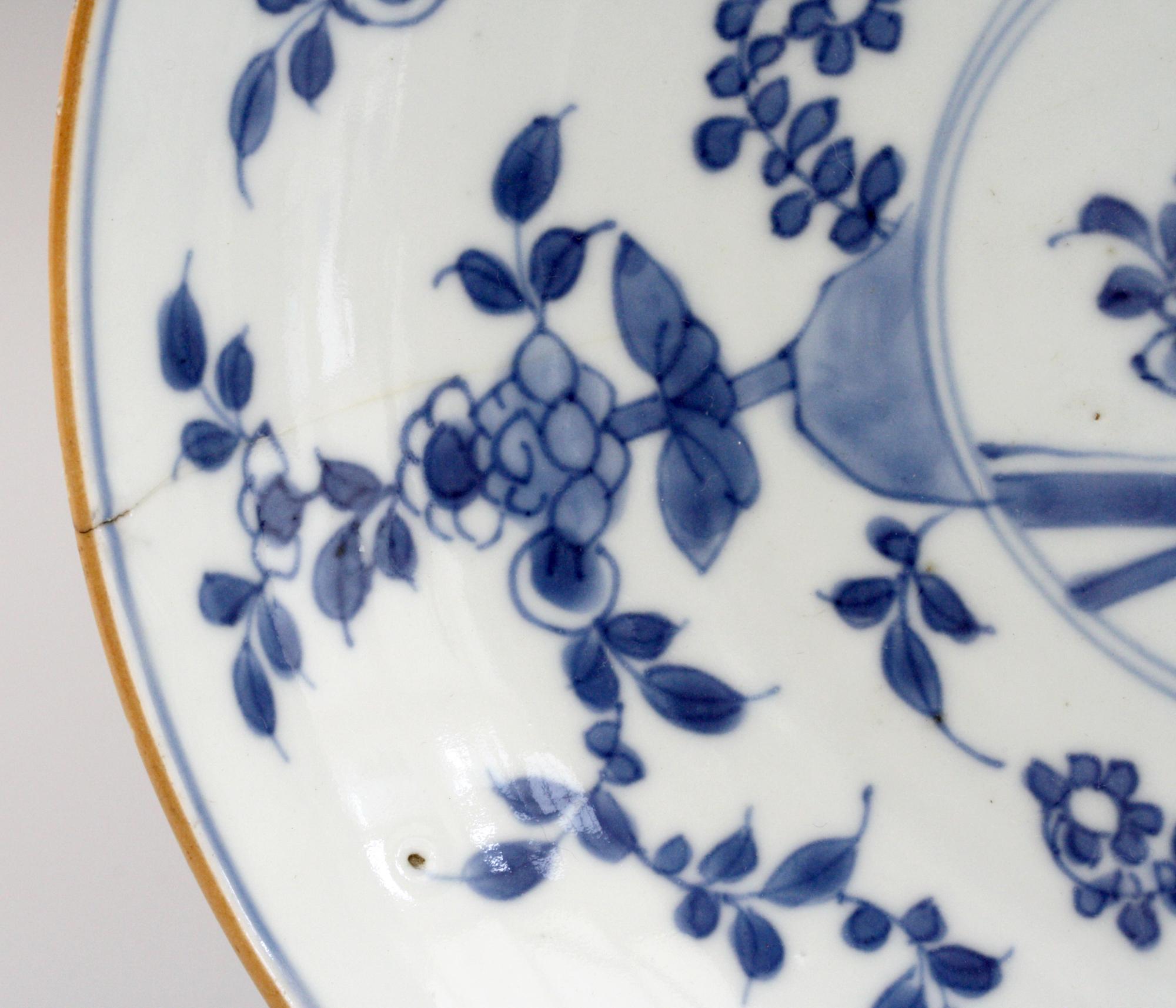 A finely made pair Chinese Kangxi blue and white floral decorated porcelain plates. The plates are of shallow bowl form with flowering roses around the inside of the dish around a small central panel containing a fence and further floral designs.