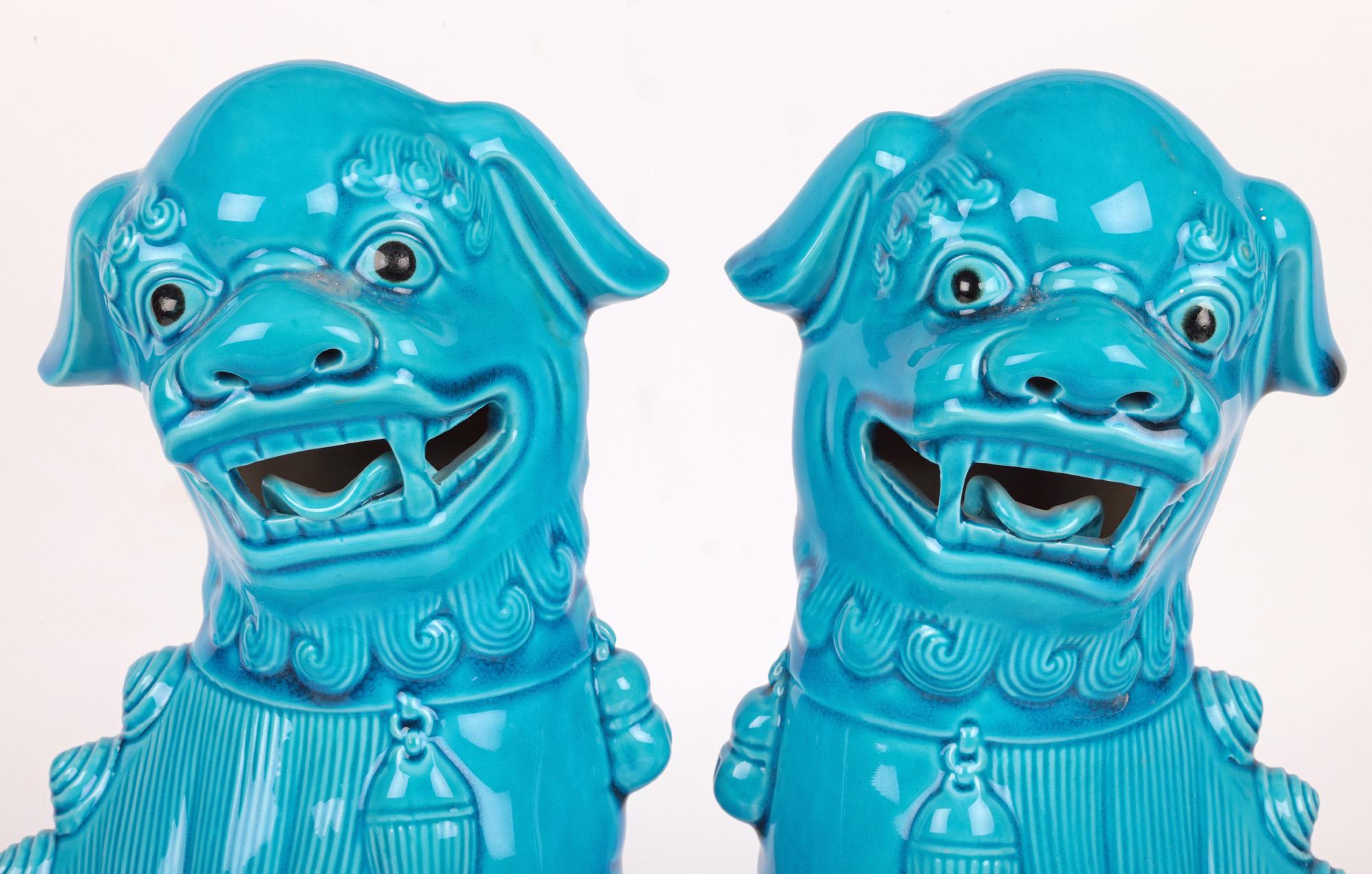 A large and attractive pair of Chinese turquoise glazed dogs of foo figures dating from the first half of the 20th century. The stylish pair hollow biscuit porcelain figures stand raised on a rectangular base and are looking sideways with open