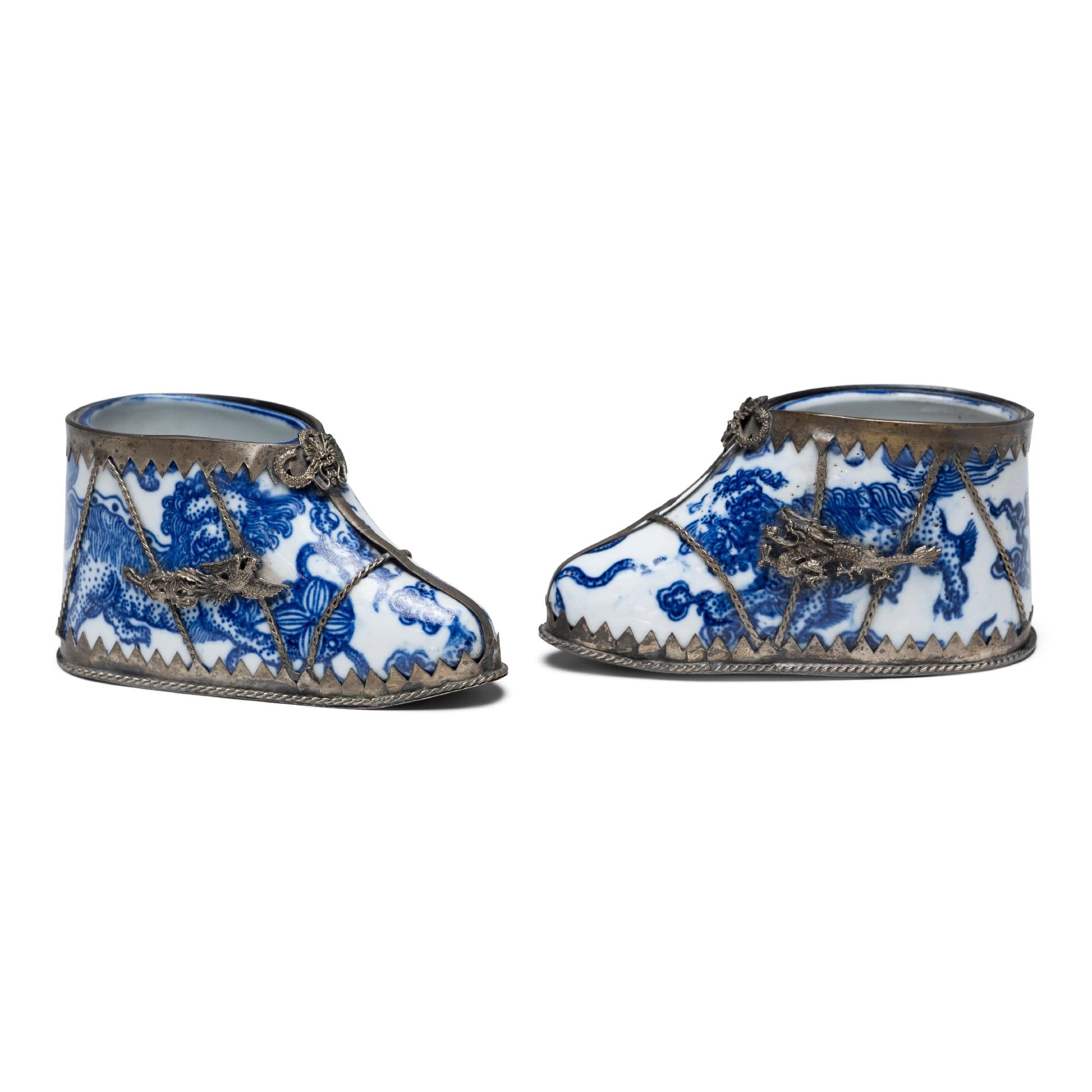 These dainty porcelain slippers are shaped to resemble a lotus bud and recreate the pointed silk shoes that enhanced the diminutive shape of bound feet. The porcelain lotus slippers are glazed with a blue-and-white design of guardian fu lions
