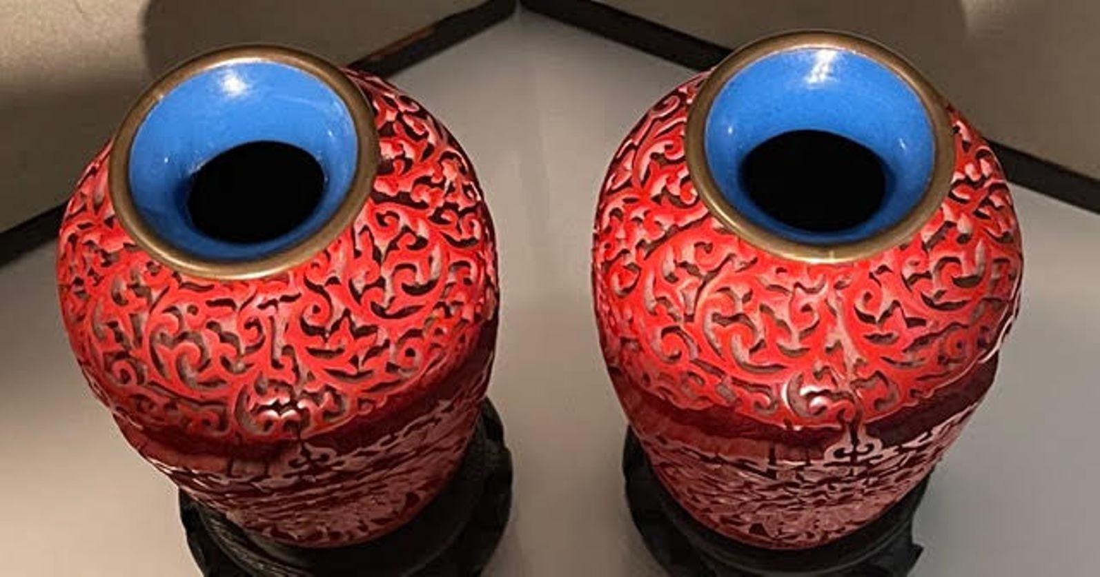 Beautiful pair of Chinese cinnabar vases with elaborate carving on the exterior and a blue accented interior. Includes vase stands.