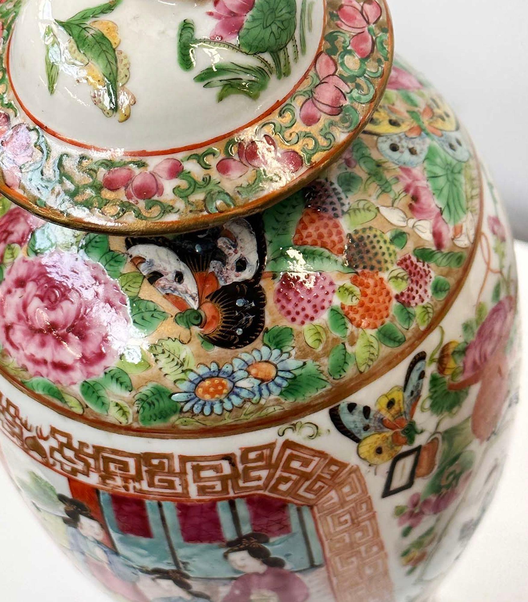 Pair of Chinese traditional Famille Rose Canton vases with great hand-painted details such as depictions of daily life, traditional Chinese scenes, botanical figures and butterflies. Each vase includes an ornate lid with a foo dog on top. Made in
