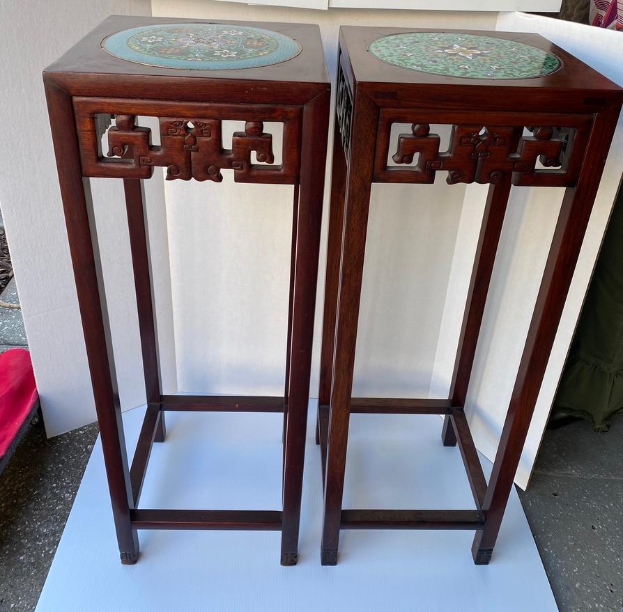 Cloisonné pair of wooden handmade tall plant stands, with hand carved trim to the side. Made of mahogany. Stretchers at the bottom and hand carved feet.