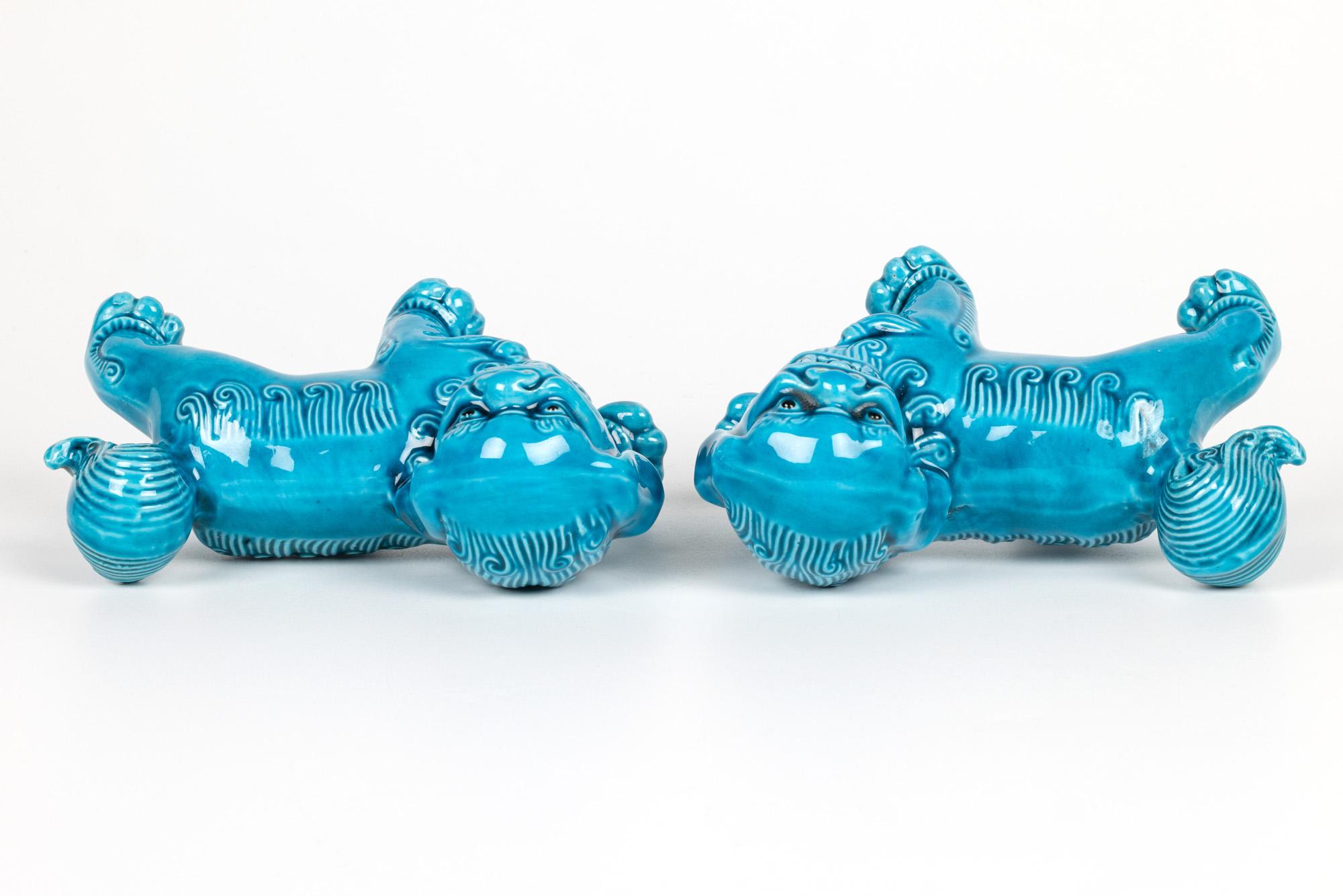A fine and attractive pair of Chinese turquoise glazed dogs of foo figures dating from the first half of the 20th century. The stylish pair hollow biscuit porcelain figures are modelled standing and  looking sideways with open mouths showing teeth