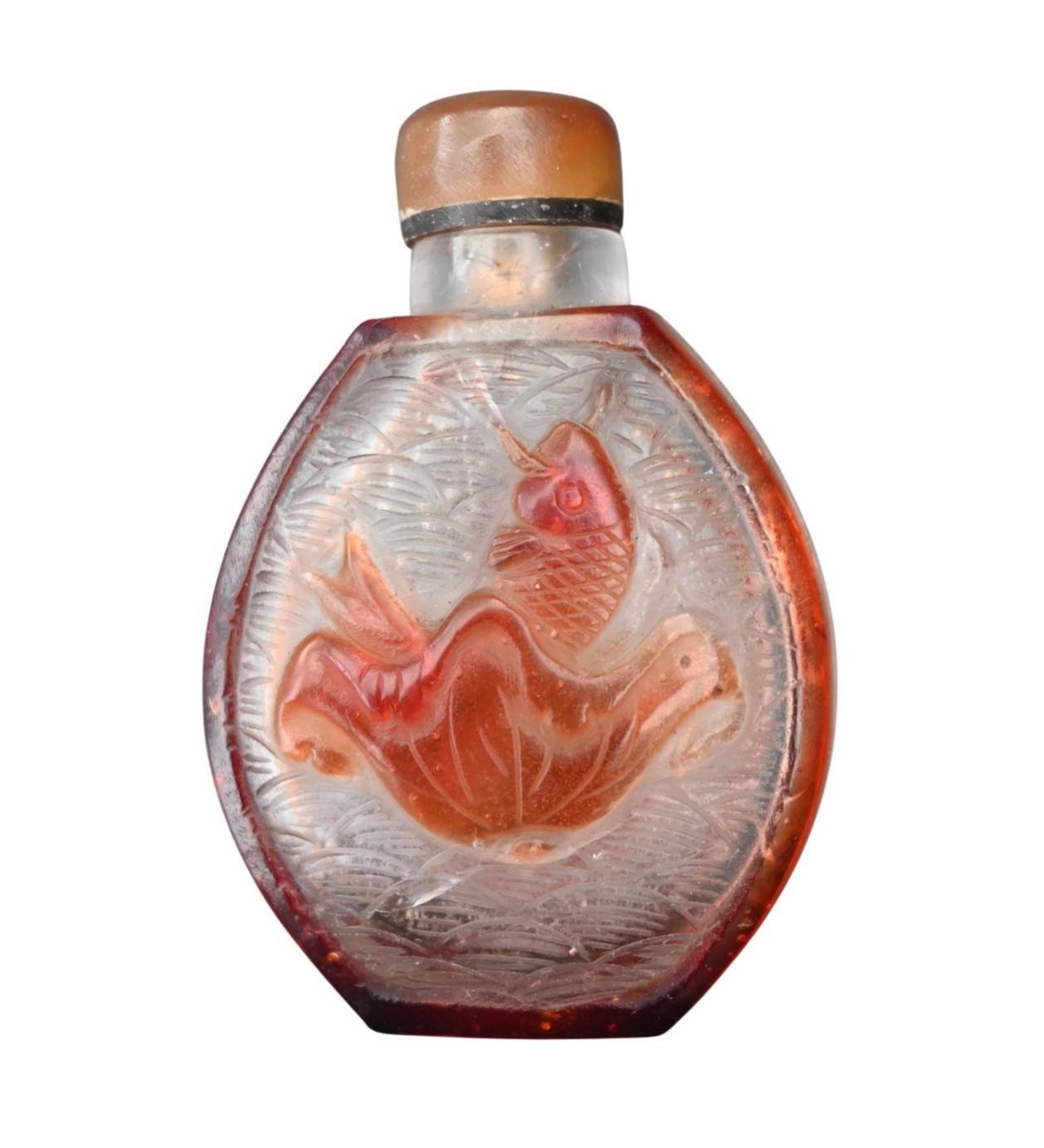 Bouteille à priser en verre de Pékin, soufflée à la main et finement sculptée en haut-relief à travers une couche rouge ambrée sur un fond clair.
Chaque face est décorée d'une carpe nageant sous une fleur de lotus, entourée de vagues incisées -