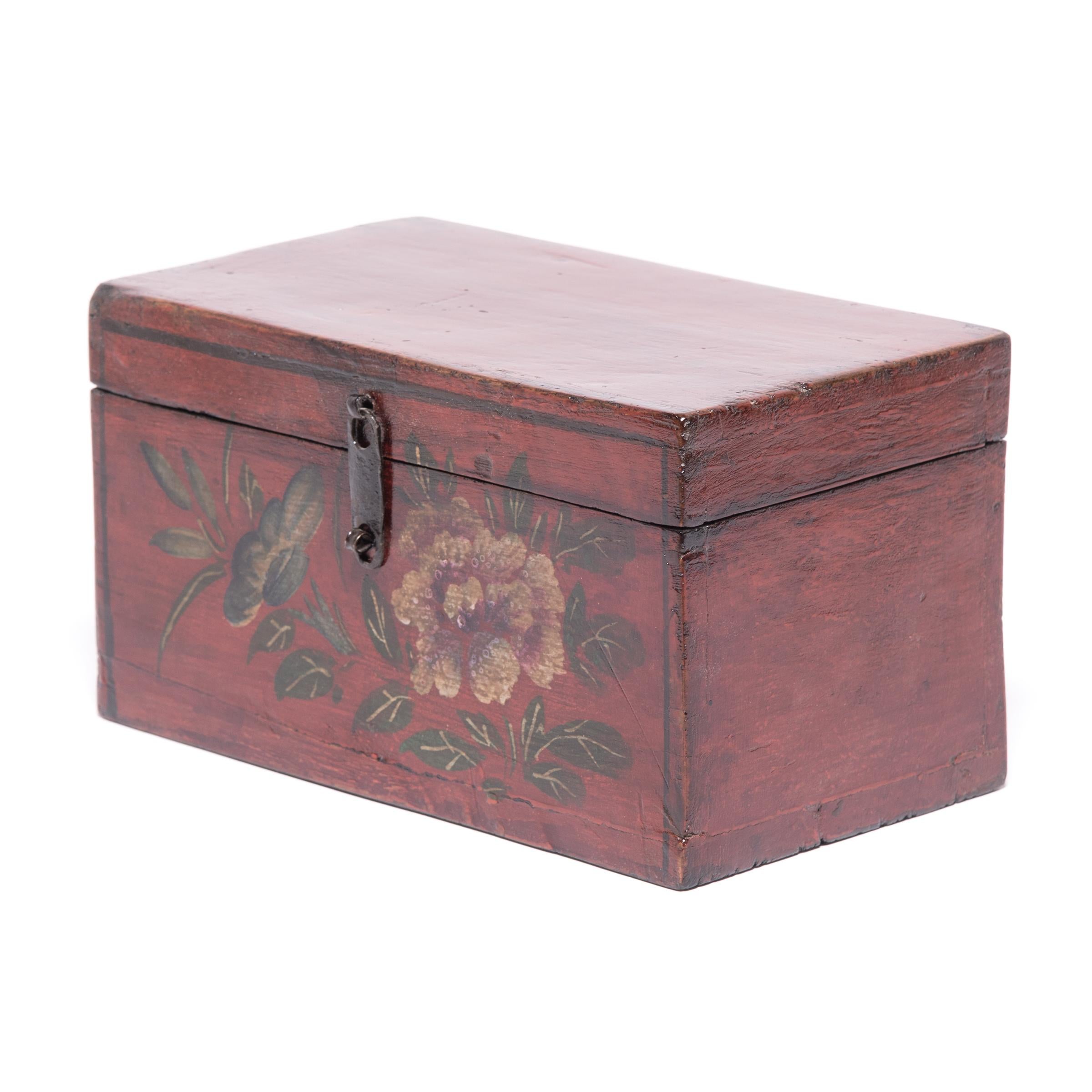Made of humble pine, this simple box was transformed by coats of rich lacquer and decorative painted motifs to become a fitting container for treasured objects. Crafted in the early 20th century, this treasure box is adorned with a blossoming peony,