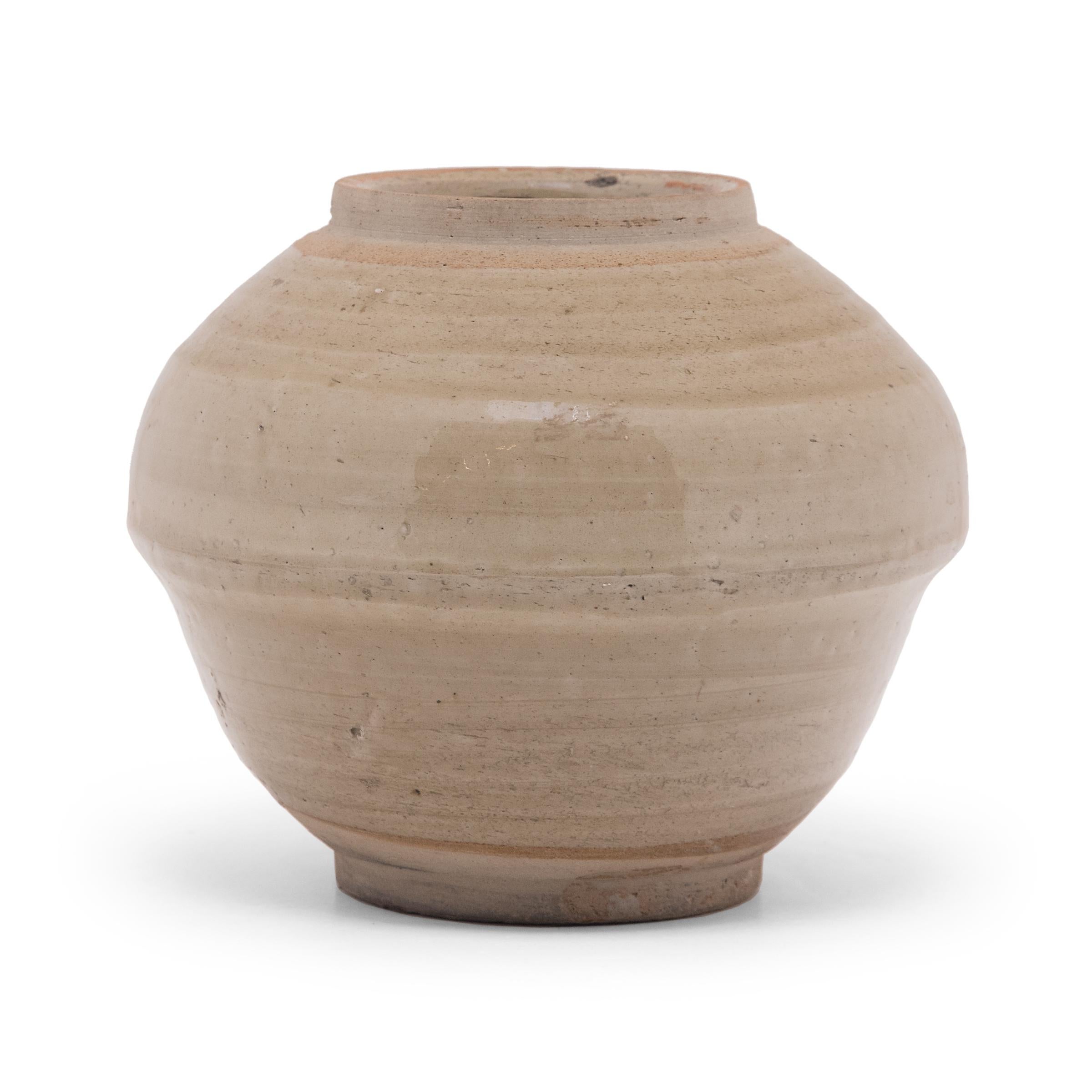 This petite ceramic jar dates to the mid-19th century and was once used for storing food or condiments in a Qing-dynasty kitchen. The jar has high shoulders that extend past the tapered lower half, a form similar to a covered rice bowl. A glossy,