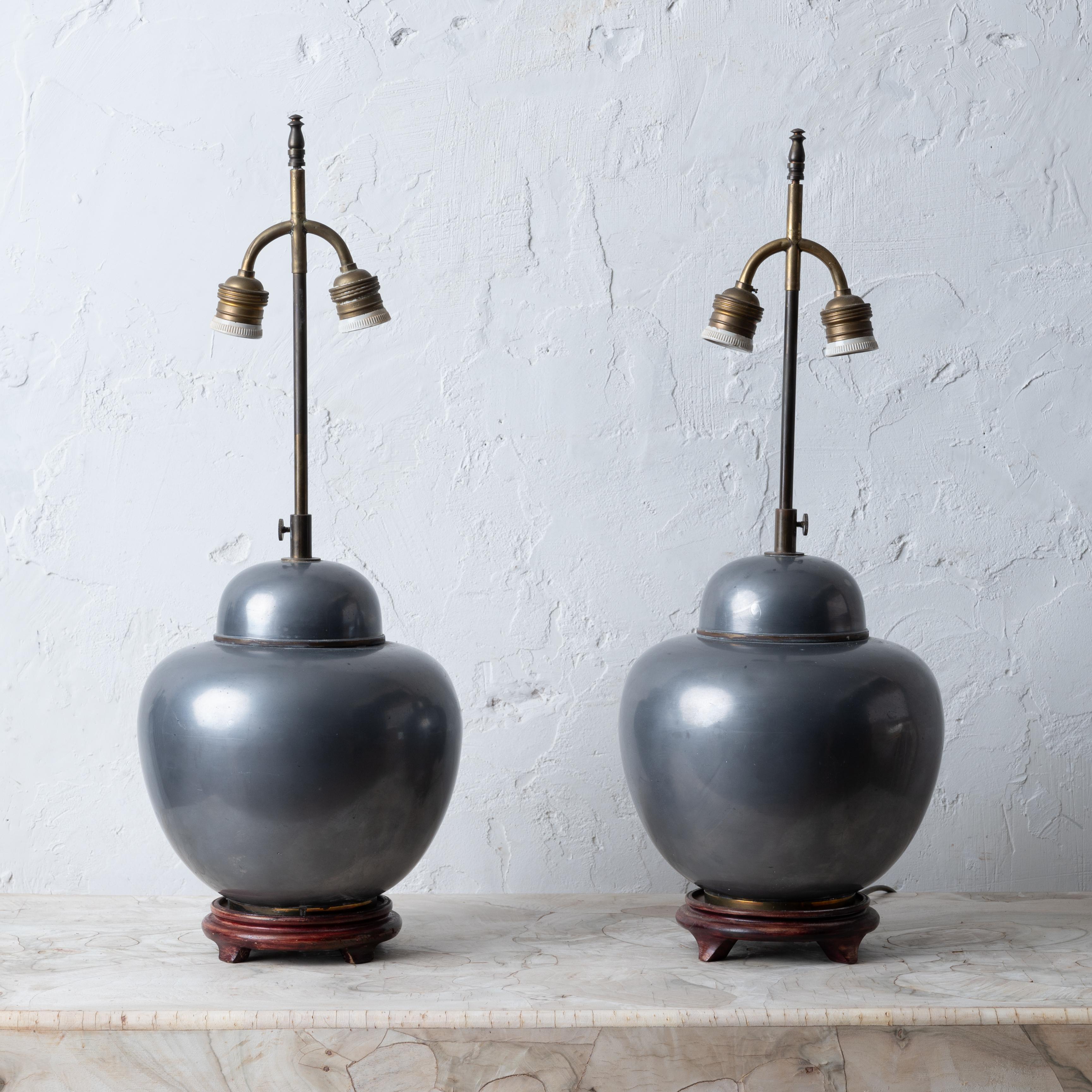 A pair of Chinese pewter ginger jar lamps on wood bases, mid-20th century.

9 inches wide by 23 ¾ inches tall extended;  pewter jar 11 inches tall on base

