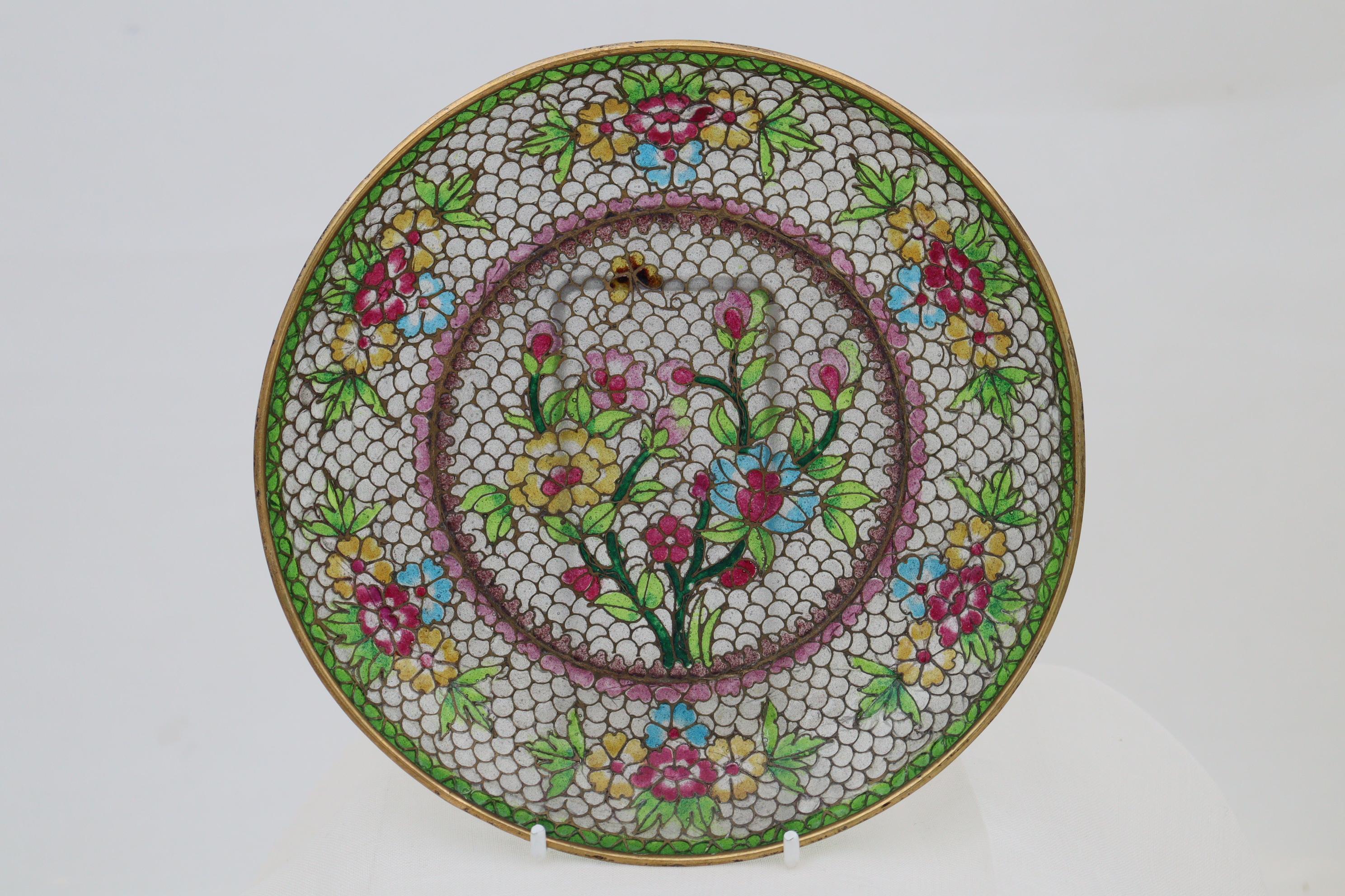 This Chinese plique-a-jour (French for glimpse of the day) dish is effectively a small stained glass window, decorated with a spray of flowers and a butterfly to the centre, and smaller sprays to the rim. The glass is held in small cells made of