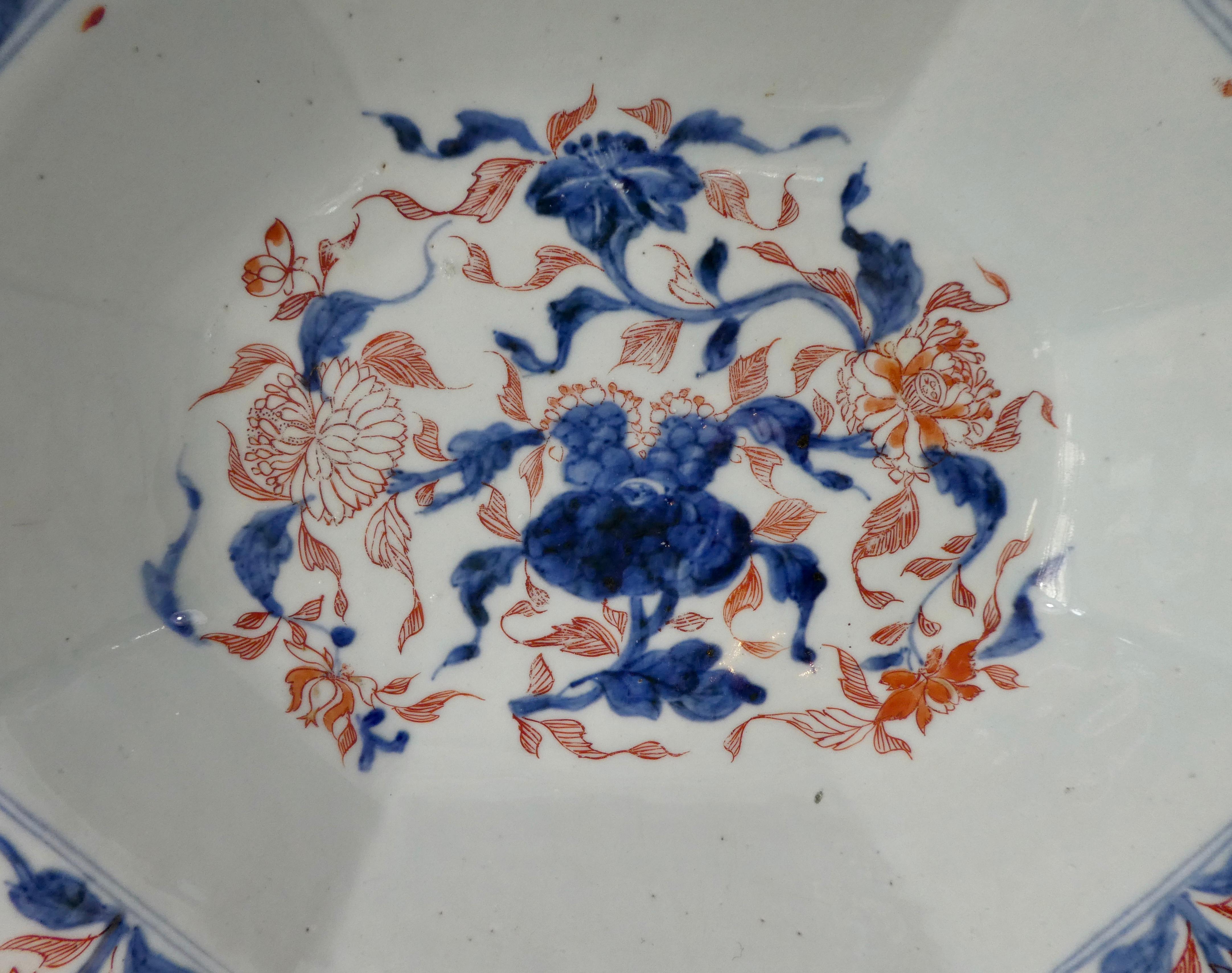 An unusual and large Chinese porcelain barbers bowl, circa 1720, Kangxi Period. The hexagonal shaped bowl, painted to the centre, with flowering plants, in the Chinese Imari taste. The border, with further similar decorated flowering plants. With a
