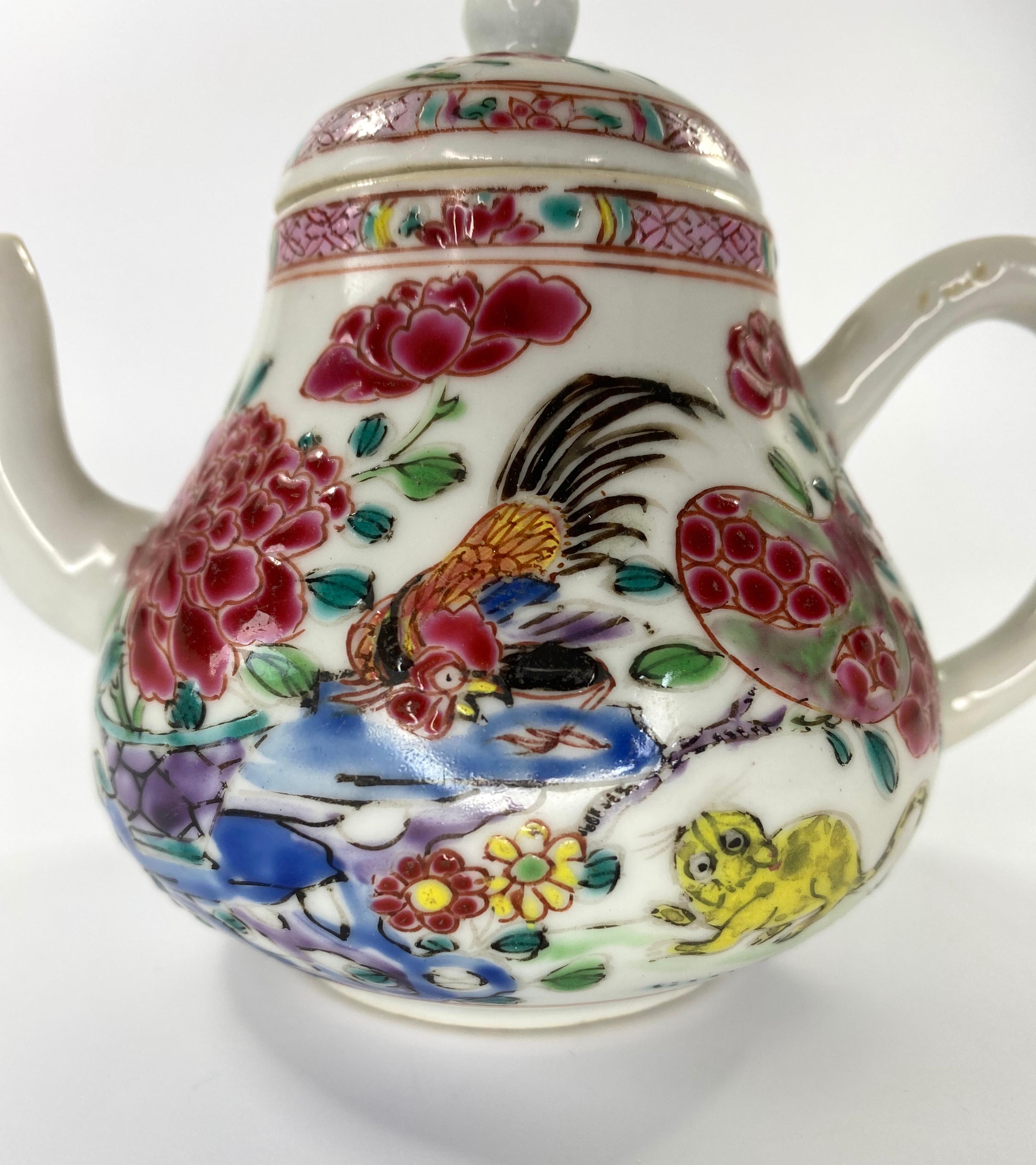 A rare Chinese porcelain teapot, circa 1740, Qianlong Period. Hand painted to both sides, in fencai, or famille rose enamels, with a repeated, unusual scene of a cockerel , perched upon rocks, being pursued by a yellow cat. The cockerel, beneath an